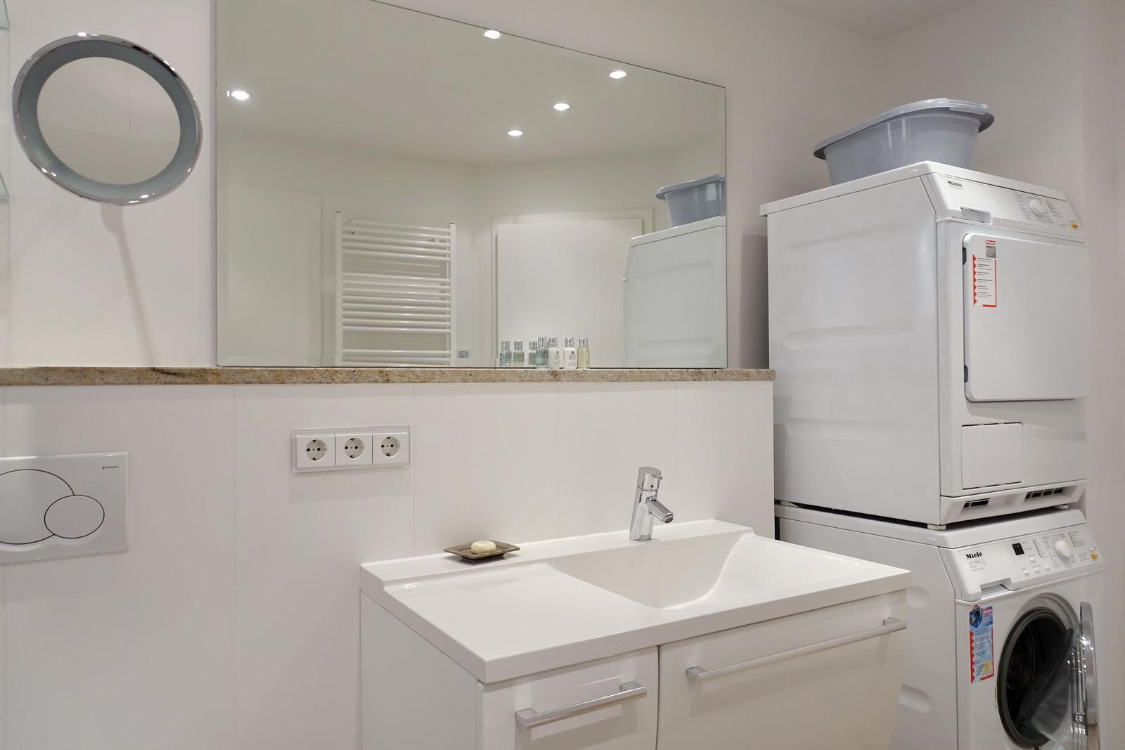Bathroom with washing machine and dryer, mirror cabinet and sink.