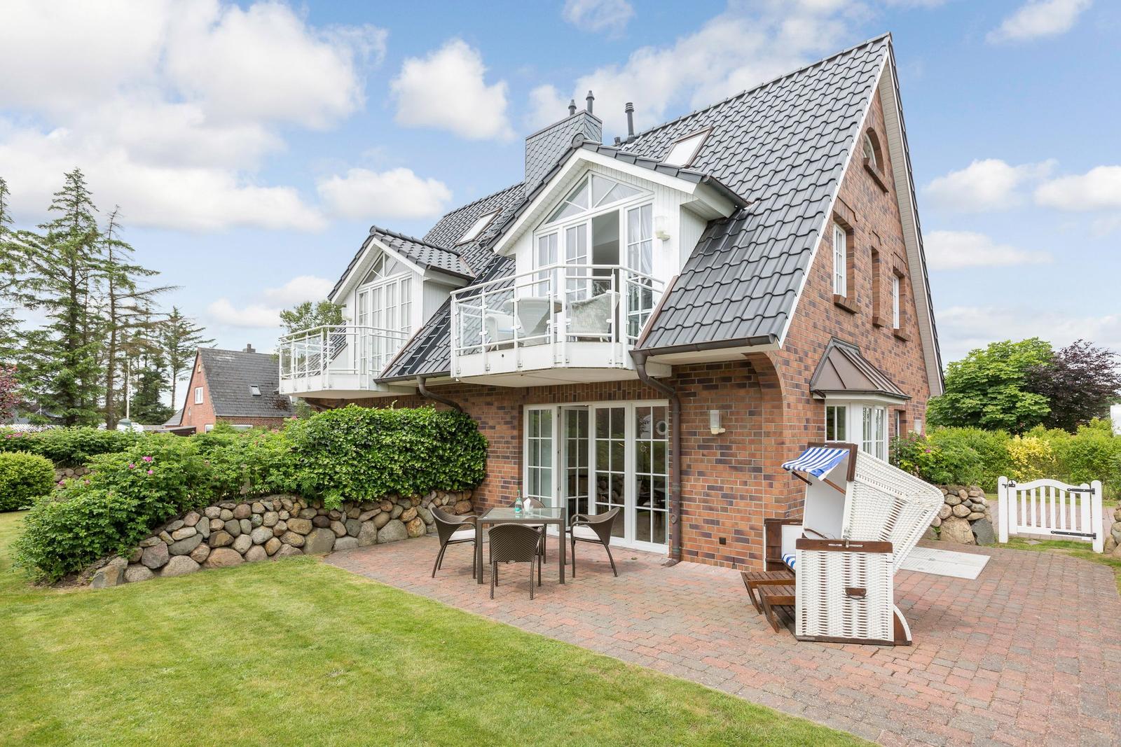 House with balcony, terrace and garden. White furniture and stone wall.