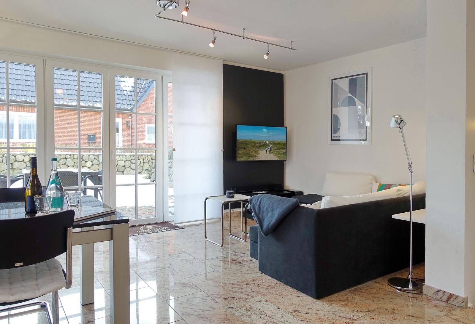 Living and dining area with sofa, TV, and terrace door.