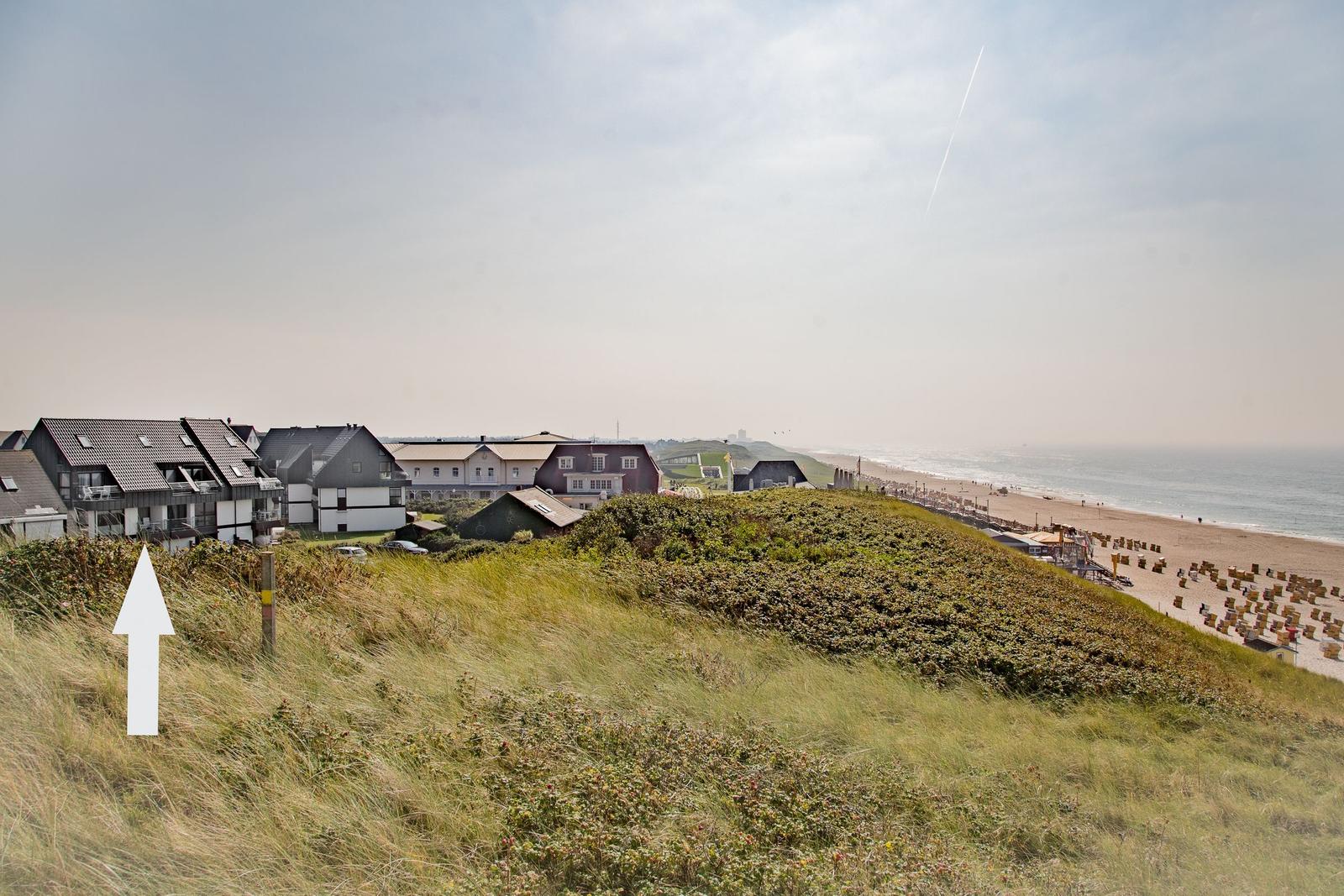House on dunes with view of beach and sea.