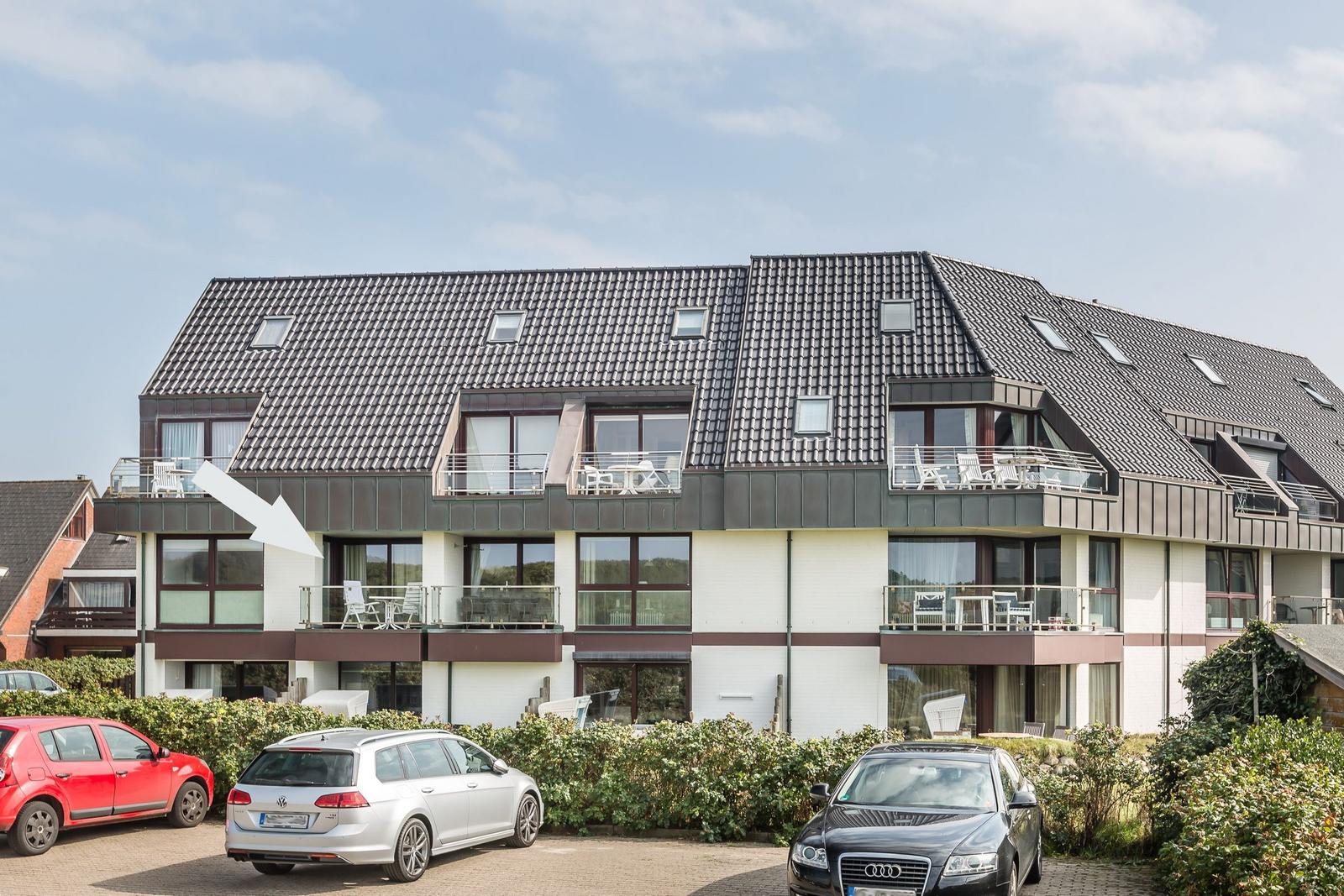 Modern multi-family house with balconies and skylights. Parking spaces in front of the building.