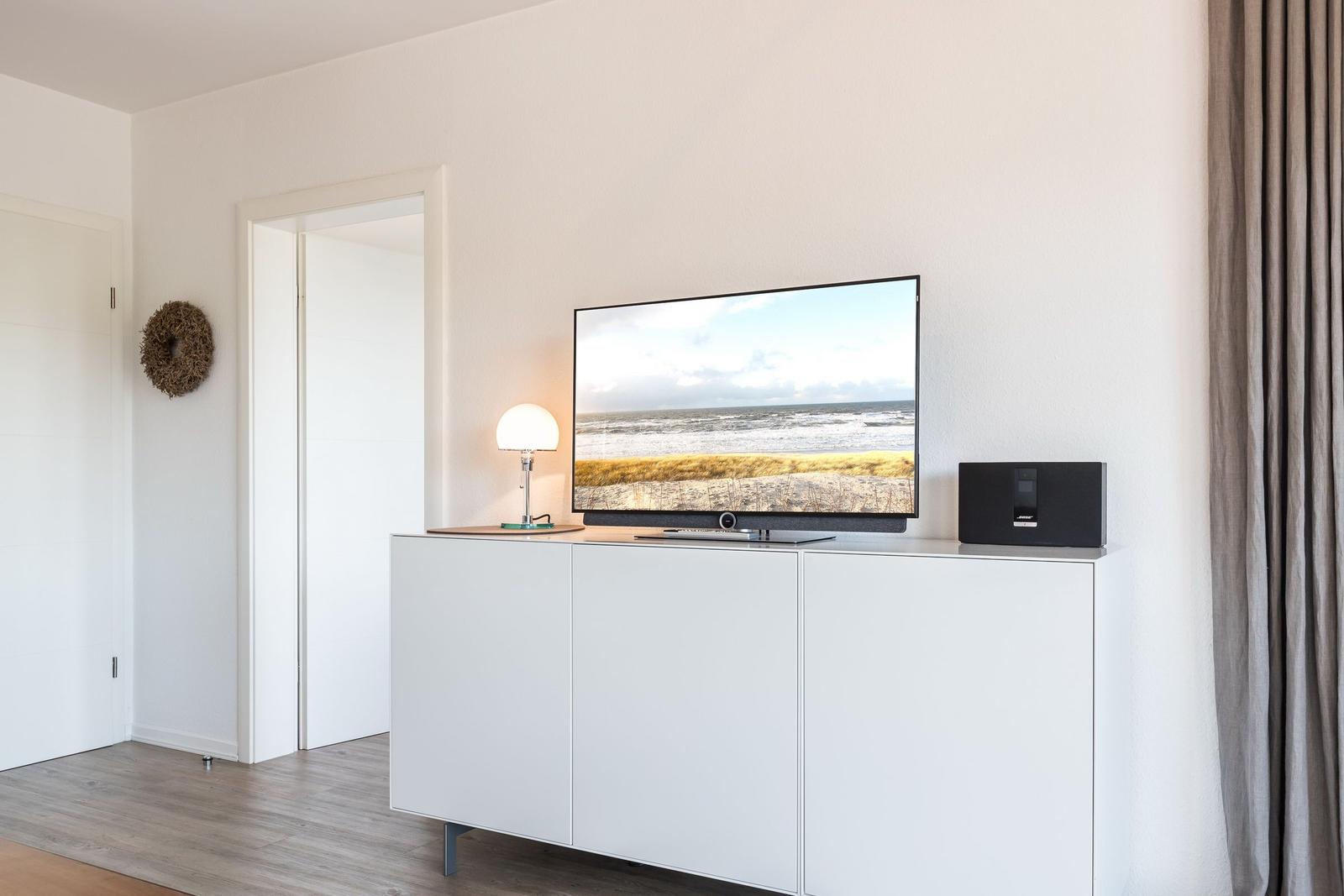 TV on white cabinet, lamp and speaker beside it