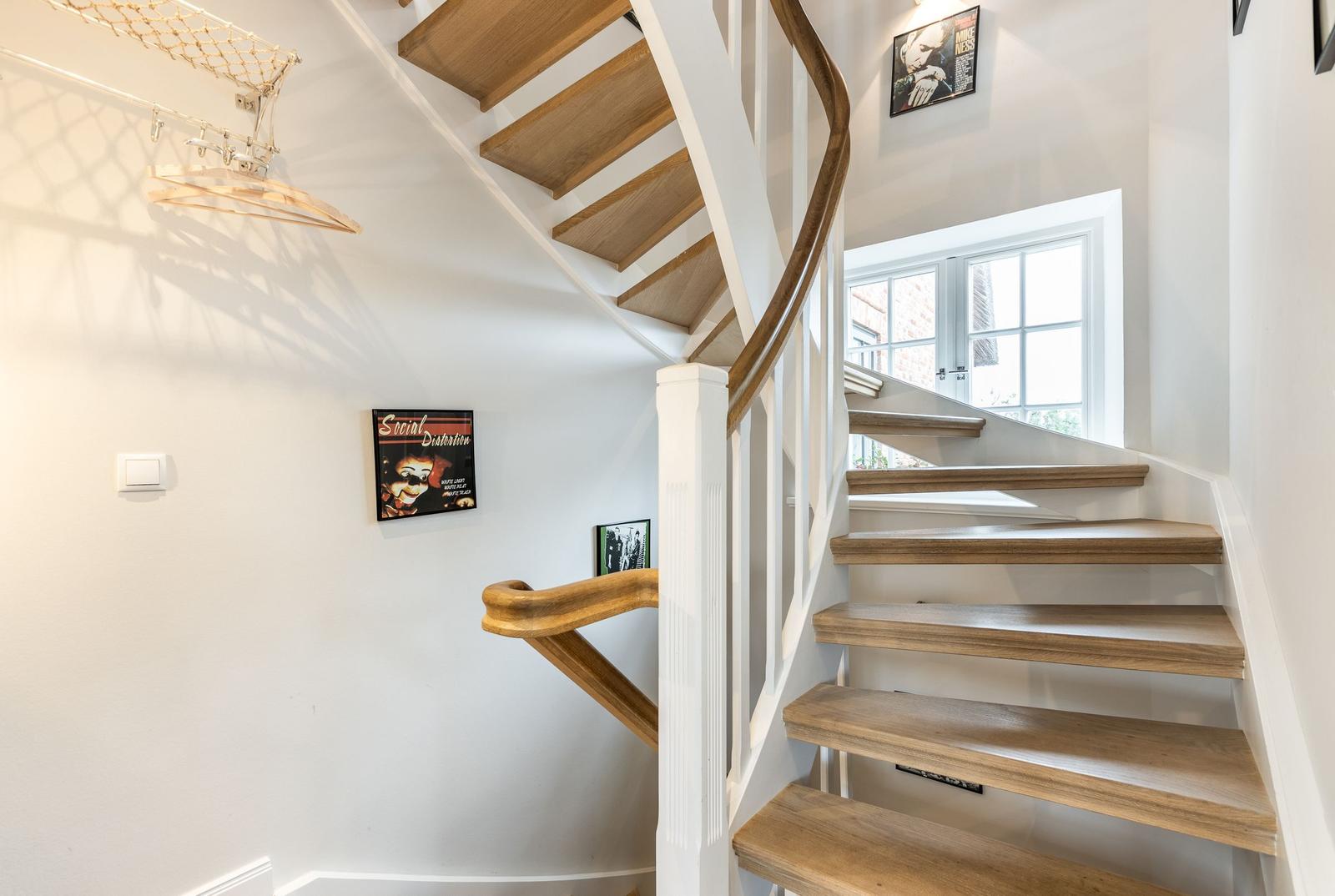 Wooden spiral staircase with white pillars and wall posters