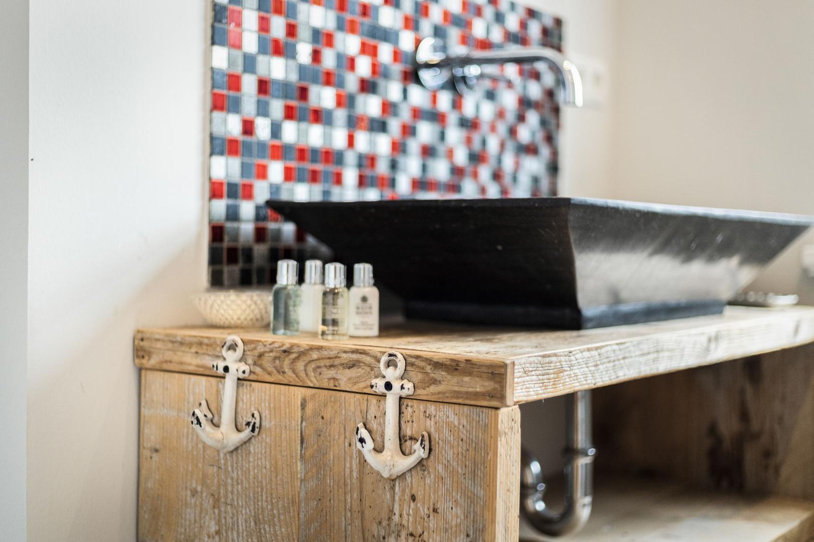 Sink on rustic wooden cabinet with anchors and mosaic wall