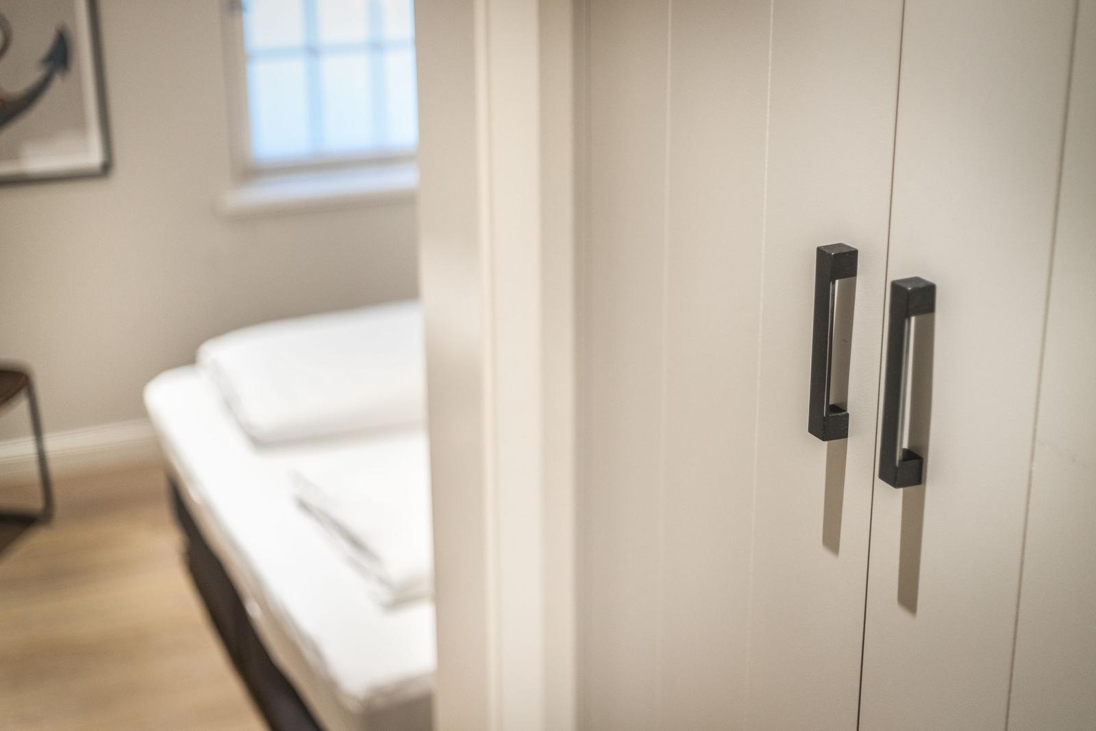 Bedroom with white wardrobe and bed. Window and picture on the wall.