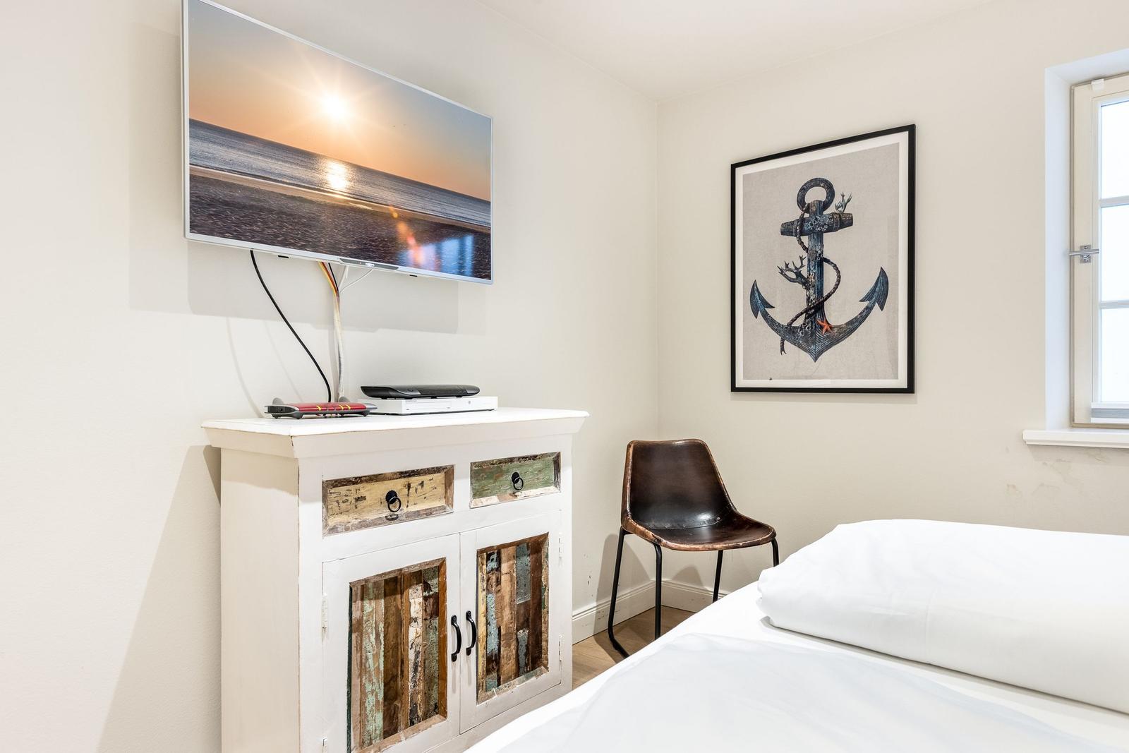 Bedroom with bed, TV, and wall art featuring an anchor