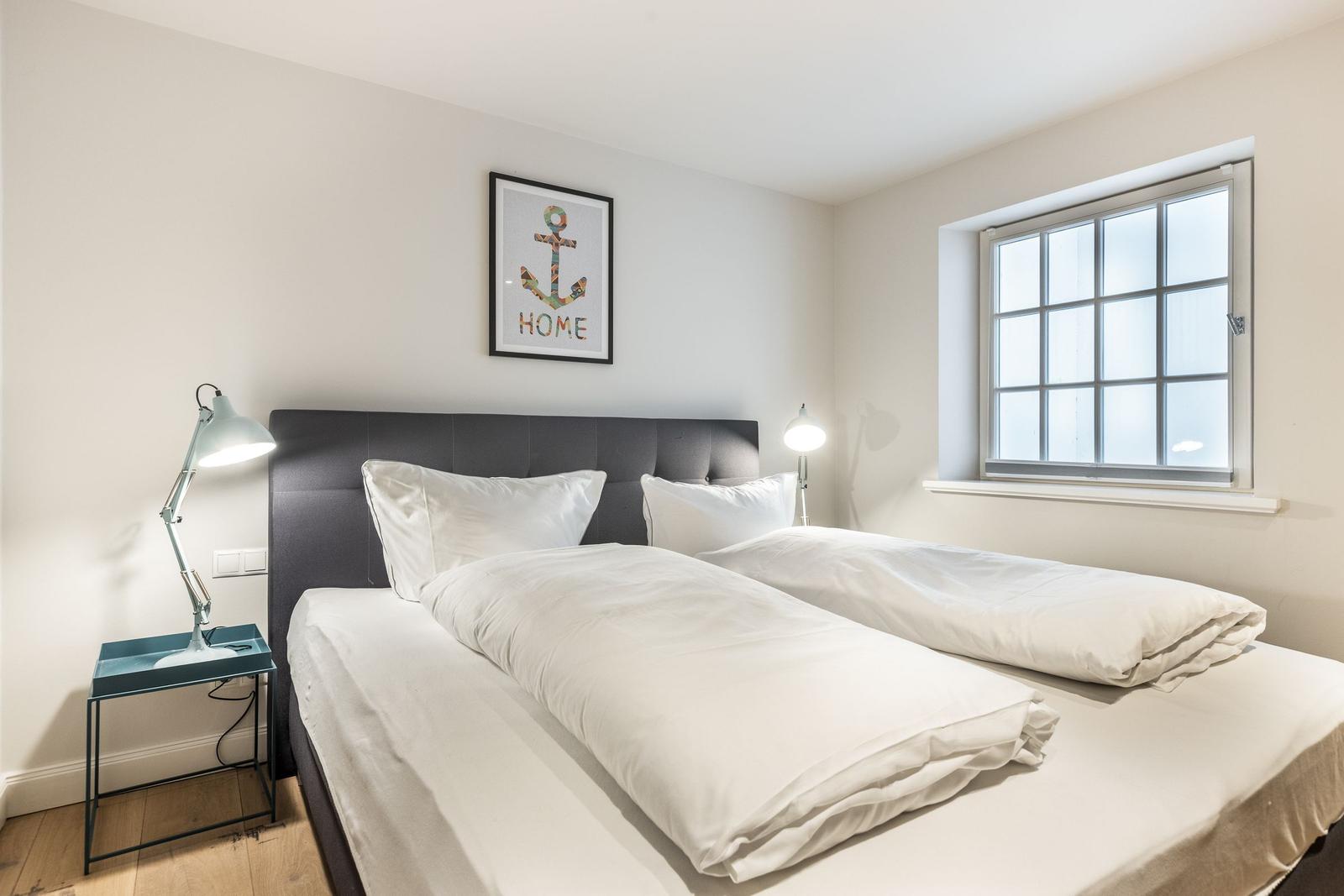 Room with double bed, window, and bedside table with lamp.