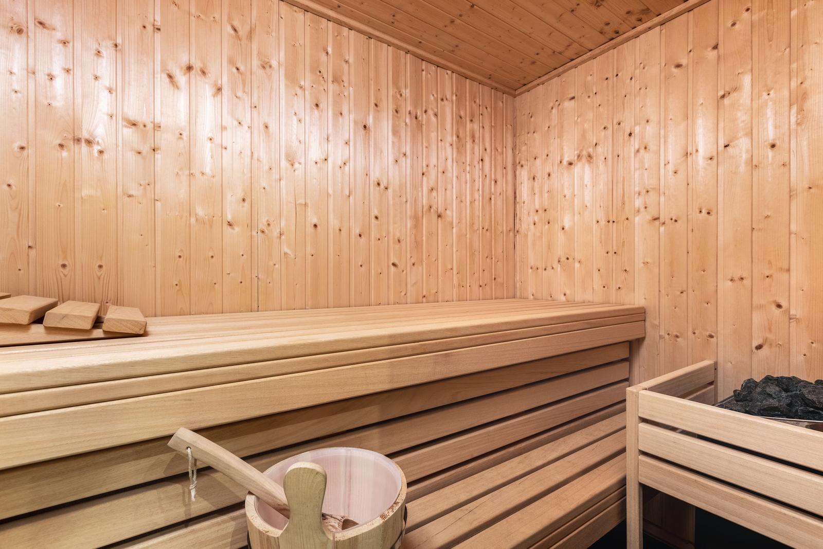 Sauna with wooden walls, bench, and wooden bucket.