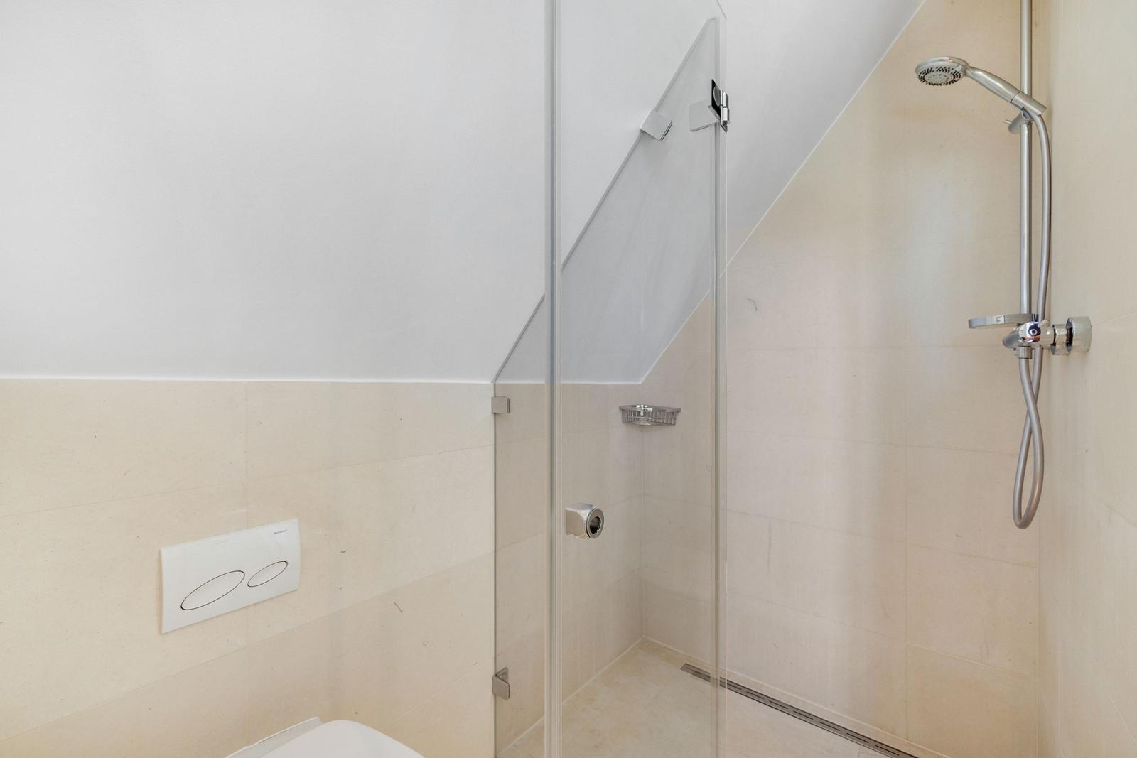 Dusche mit Glaswand und Duschbrause an der Wand