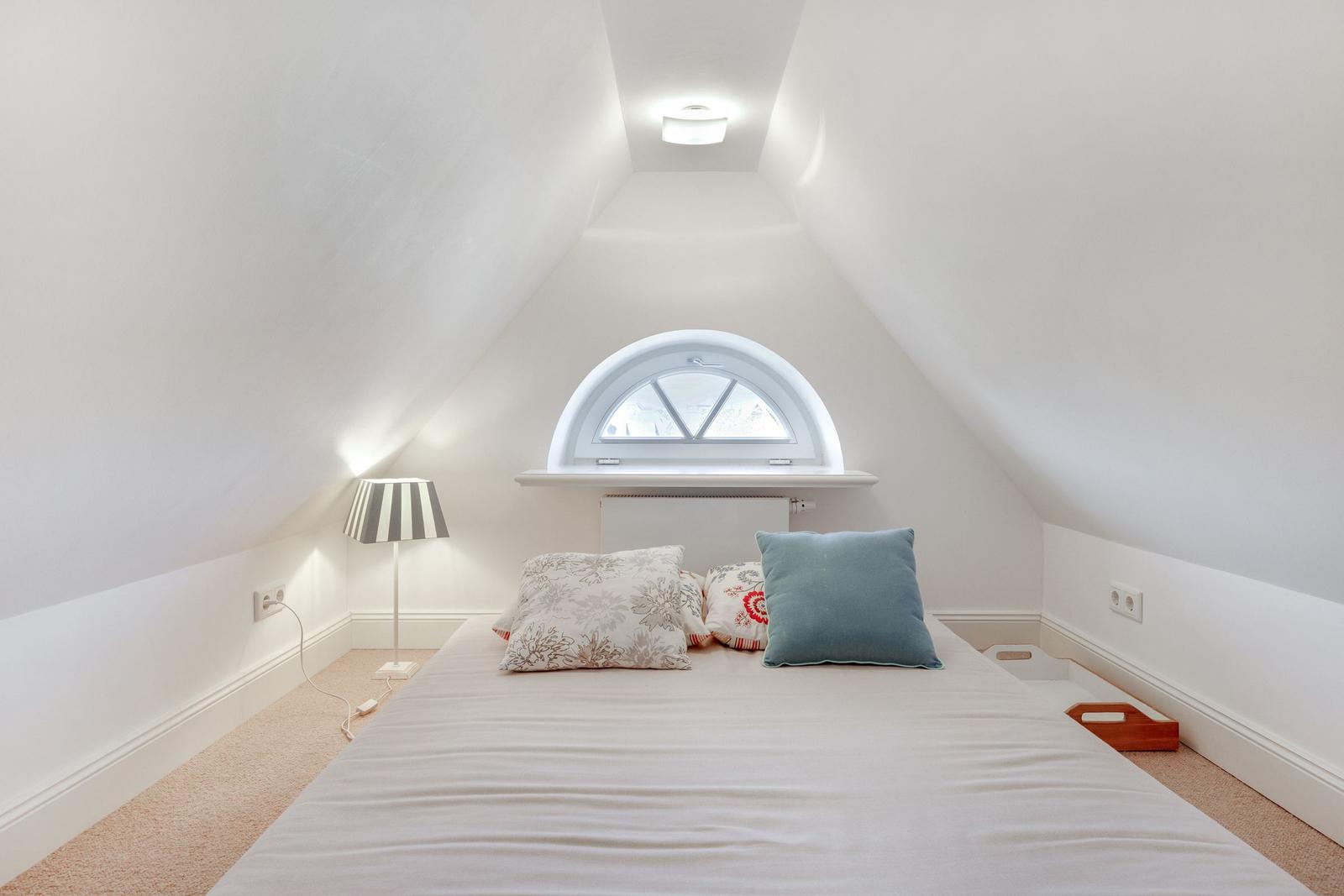 Schlafzimmer mit Dachschrägen, Fenster und Bett