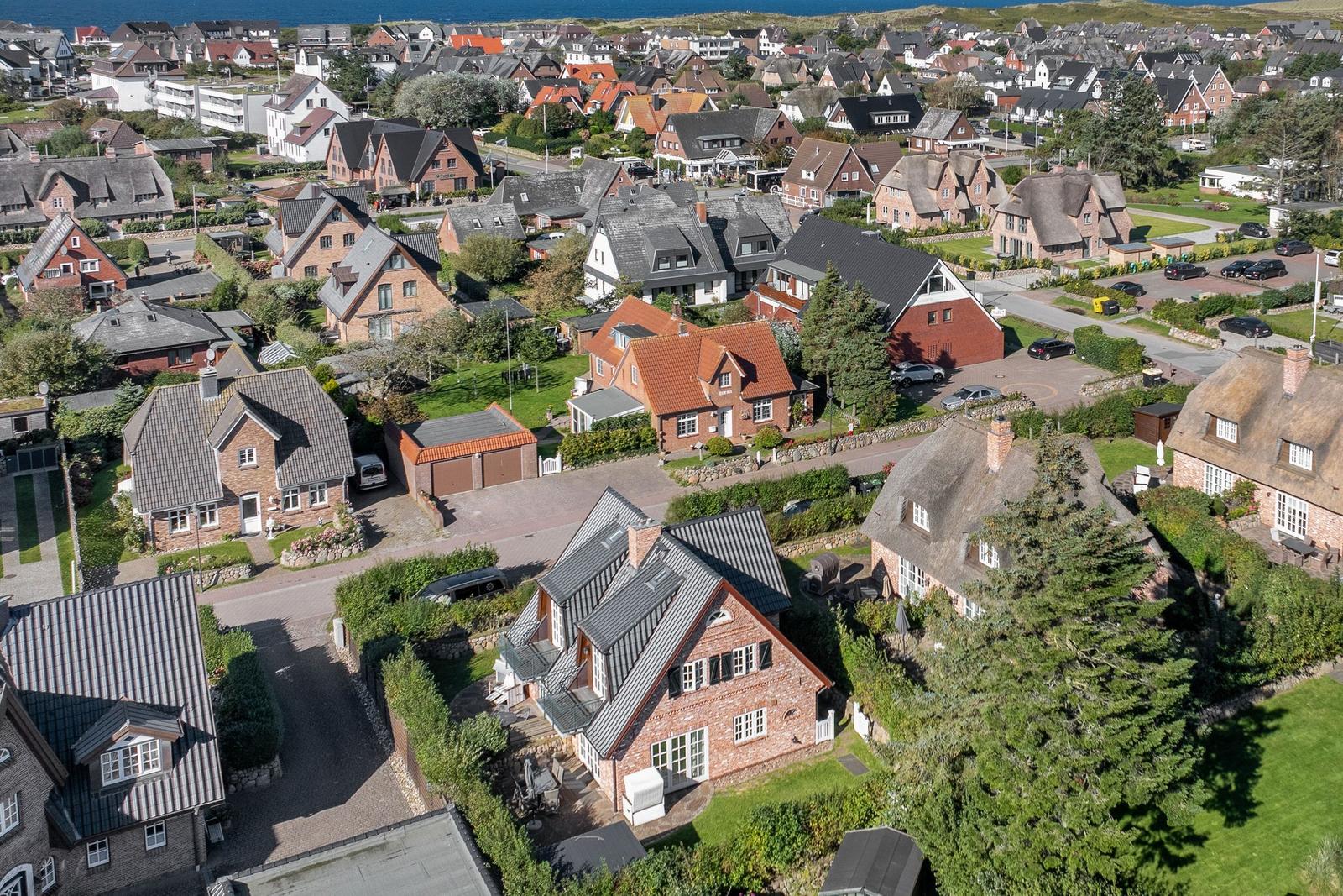 Luftbild von Häusern mit Dächern und Gärten in einer Küstenstadt.