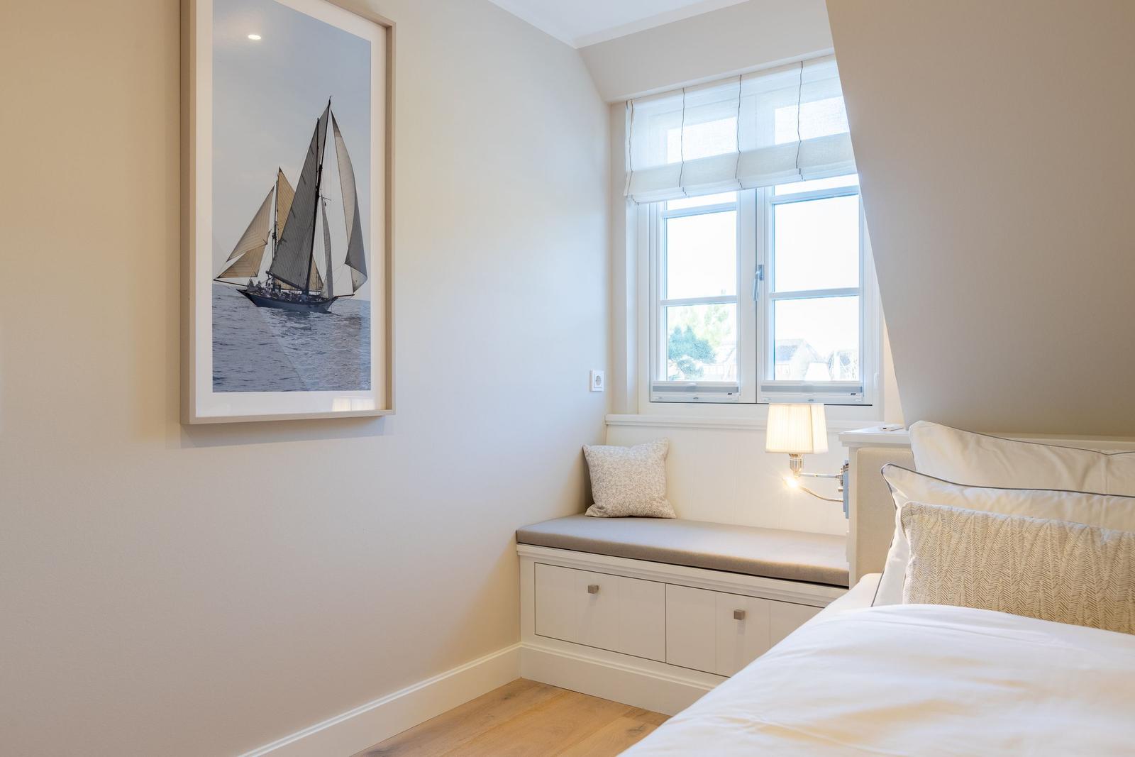 Schlafzimmer mit Fensterbank, Bett und Wandbild mit Segelboot.