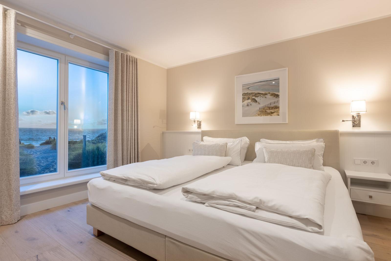 Schlafzimmer mit Blick aufs Meer und weißem Bett.