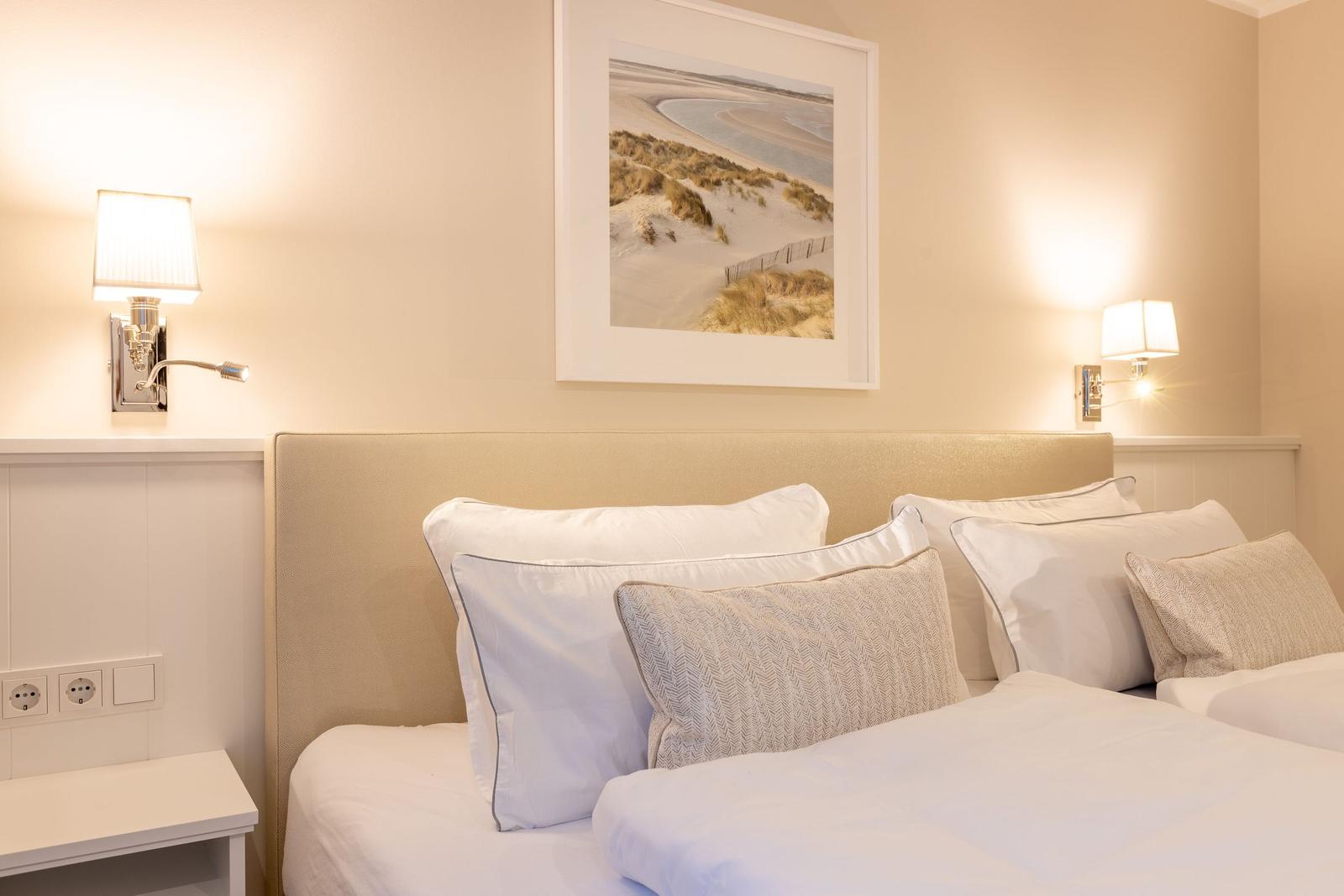 Schlafzimmer mit Bett, Kissen und Wandbild an der Wand.