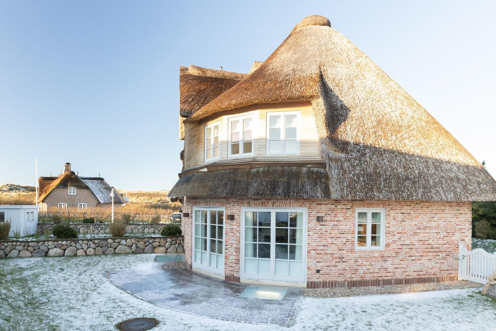 Haus mit Strohdach und Backsteinfassade. Vorderhof mit leichtem Schnee.