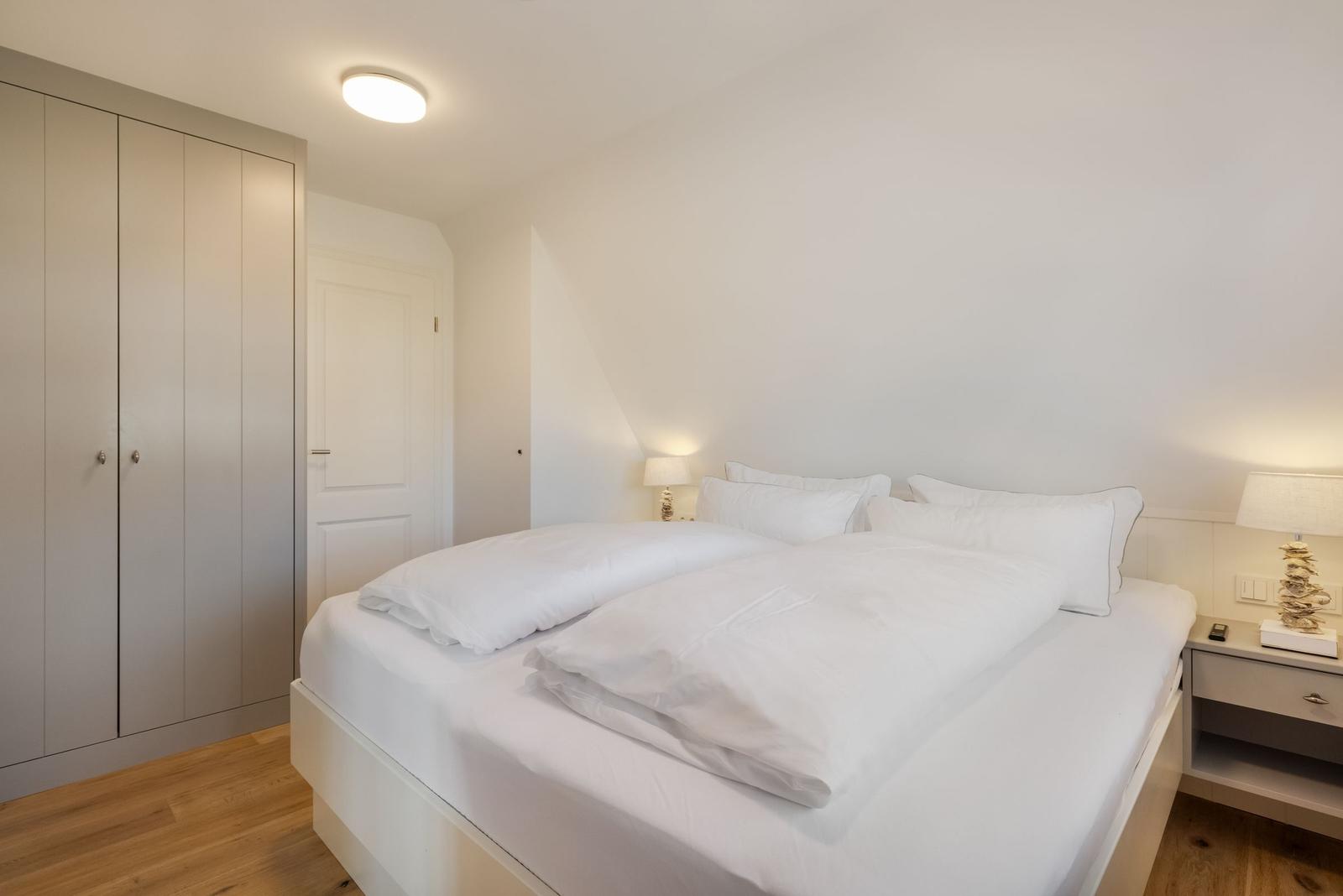 Schlafzimmer mit Doppelbett, Nachttischen und Kleiderschrank.