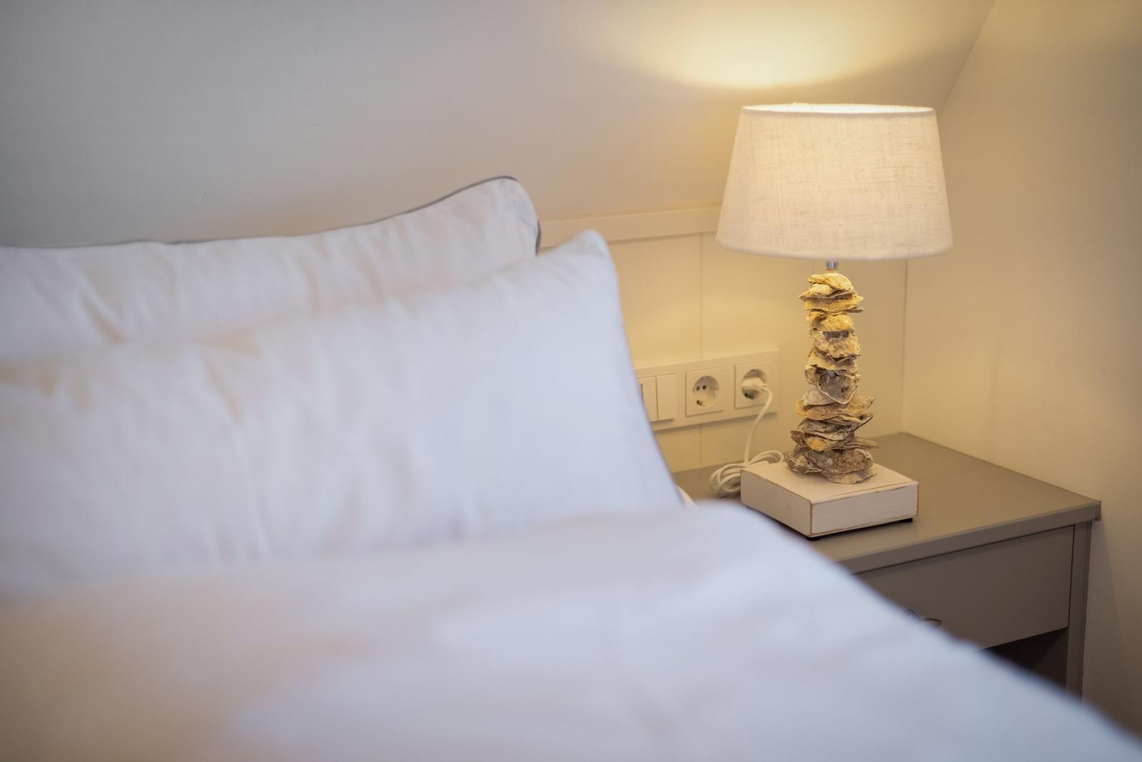 Schlafzimmer mit Bett, Nachttisch und Lampe aus Muscheln.