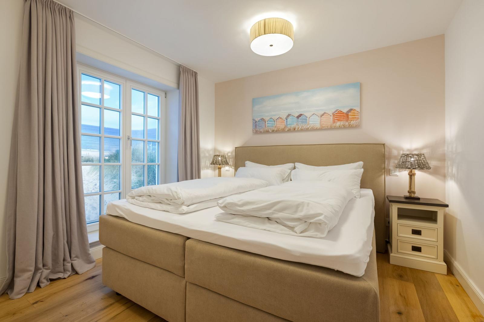 Schlafzimmer mit Bett, Nachttisch und Fenster zur Aussicht.