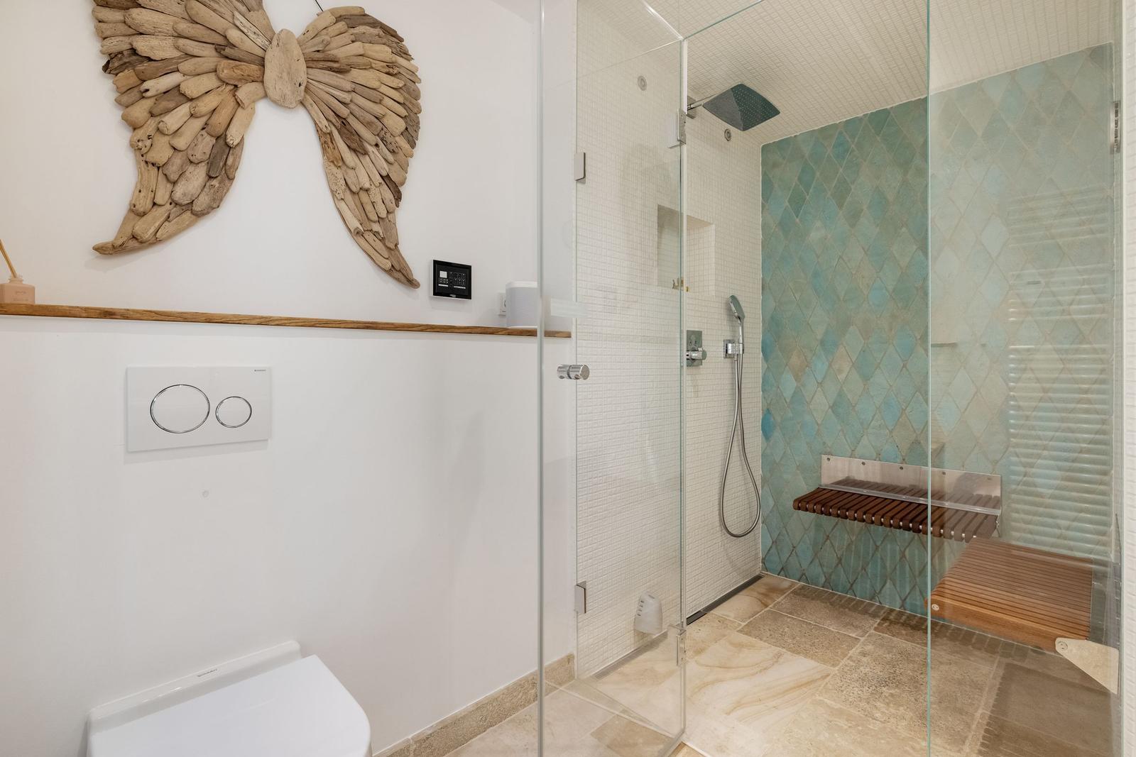 Dusche mit Glaswand, Holzbank und blauen Fliesen. Wanddekoration aus Holz.