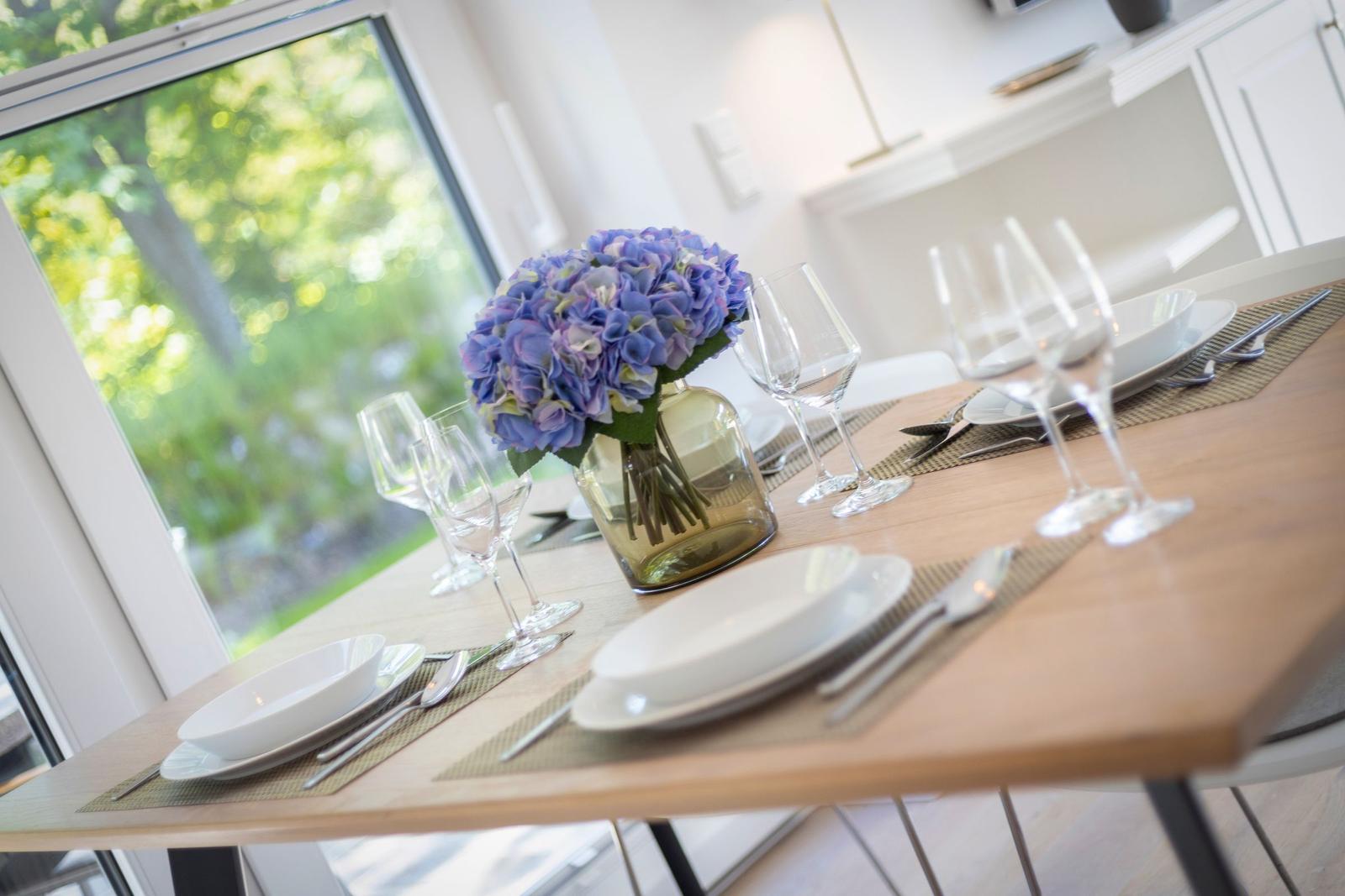Esstisch mit Platz für vier Personen, Blumenstrauß und Blick auf den Garten.