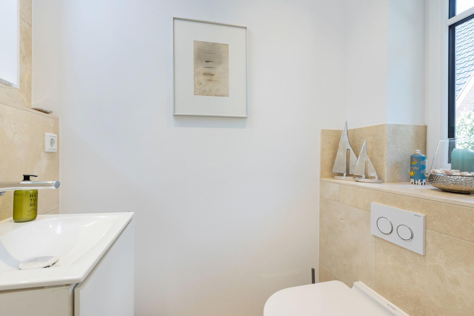 Badezimmer mit Waschbecken, Toilette und Fenster