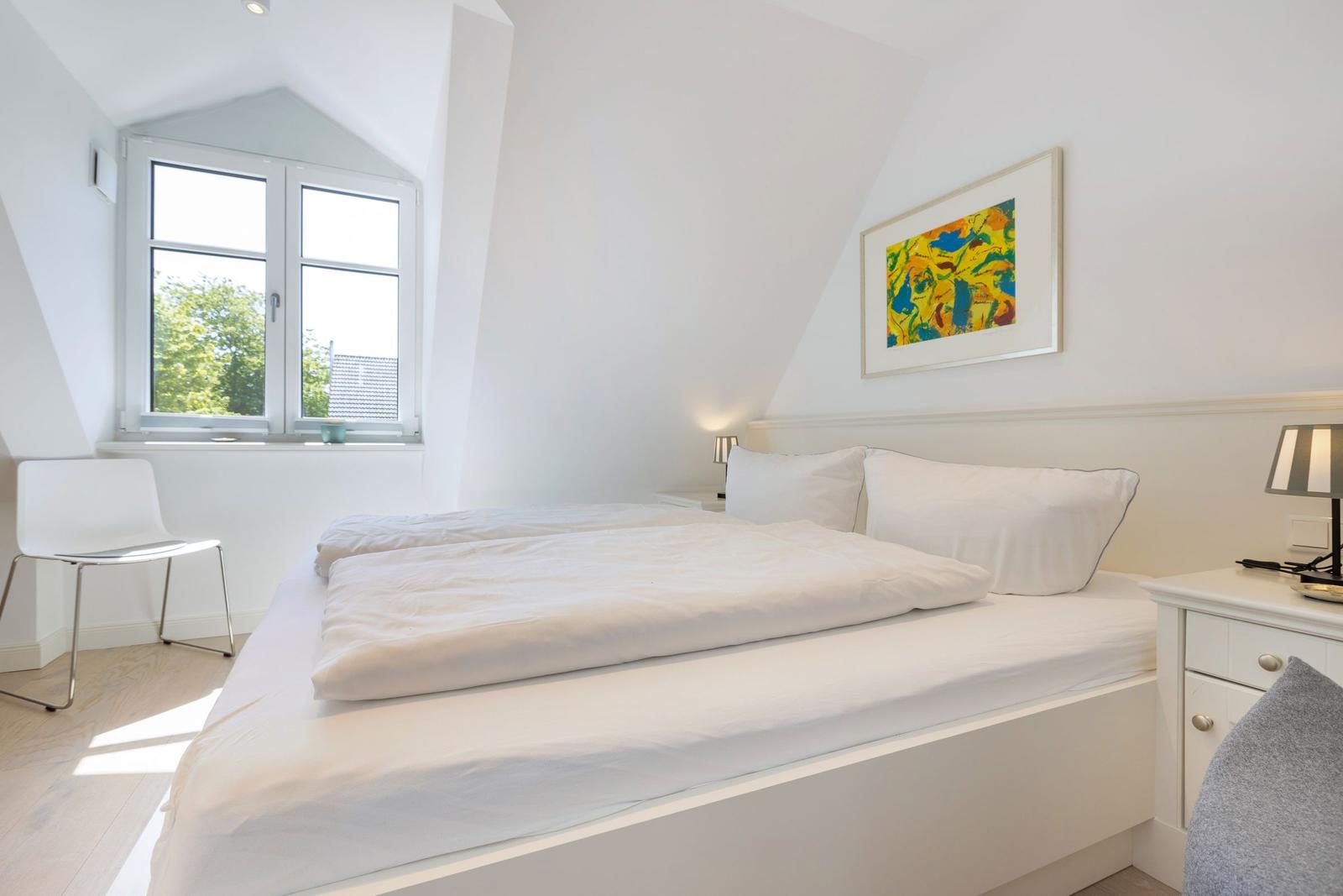 Schlafzimmer mit Doppelbett, Fenster und Kunstwerk an der Wand.