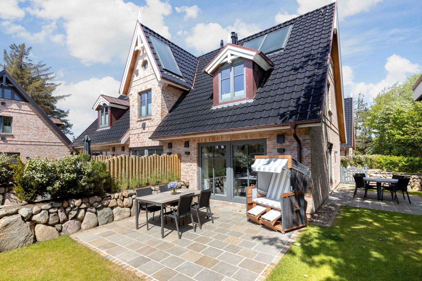 Haus mit Steinmauer, Terrasse und Garten. Holzveranda und Sitzgruppe im Freien.