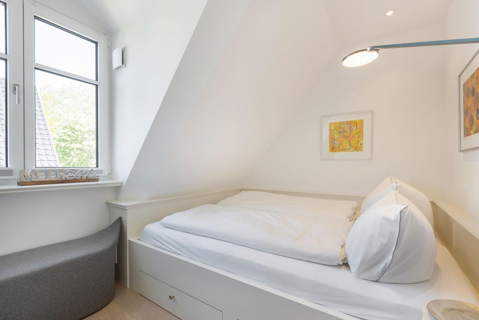 Dachgeschosszimmer mit Bett, Fenster und Wandbild.
