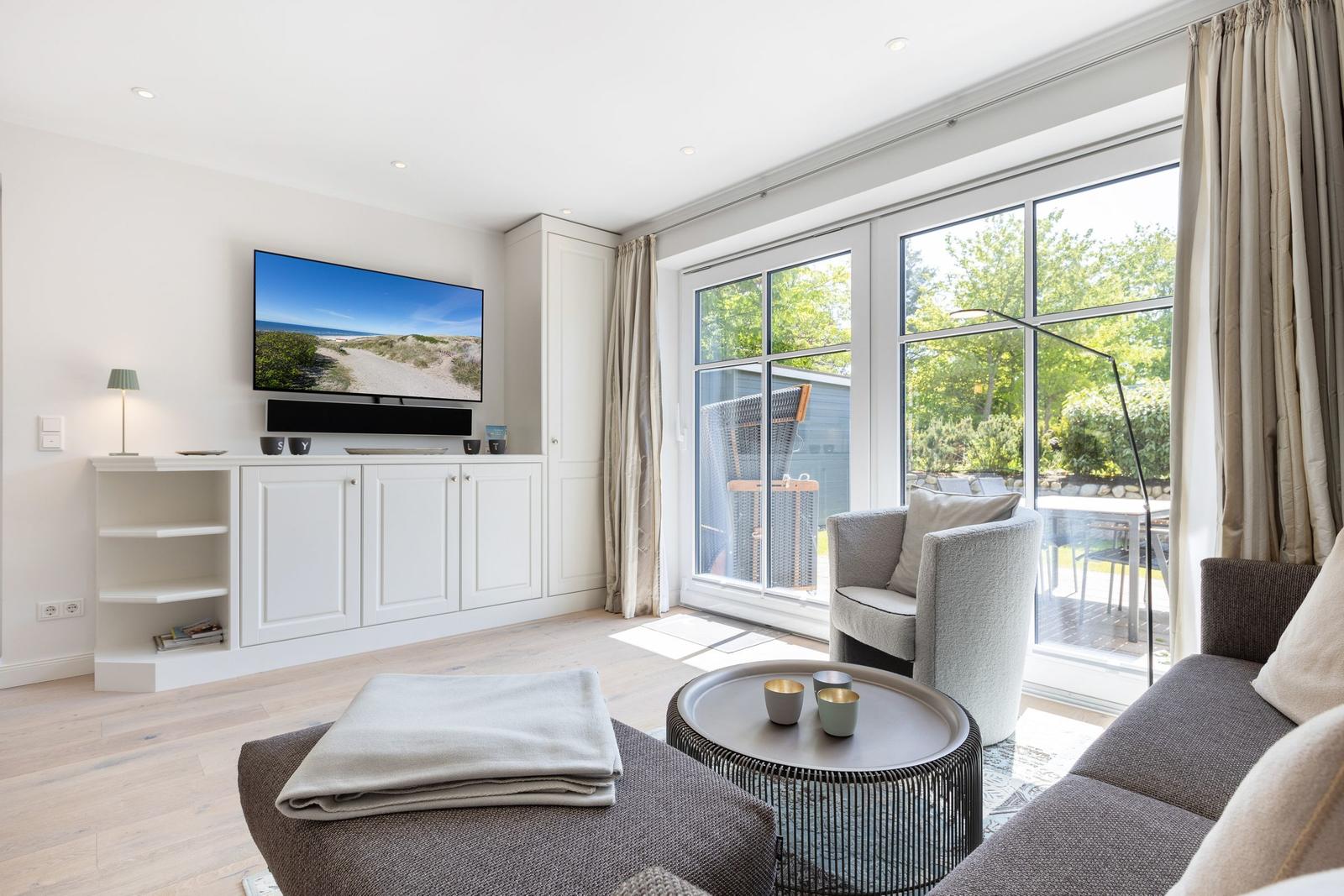 Wohnzimmer mit TV, Sofa und Blick auf Balkon.