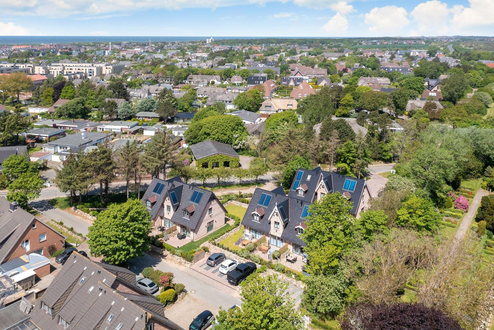 Luftbild von Häusern mit Gärten und Blick auf die Stadt und das Meer.