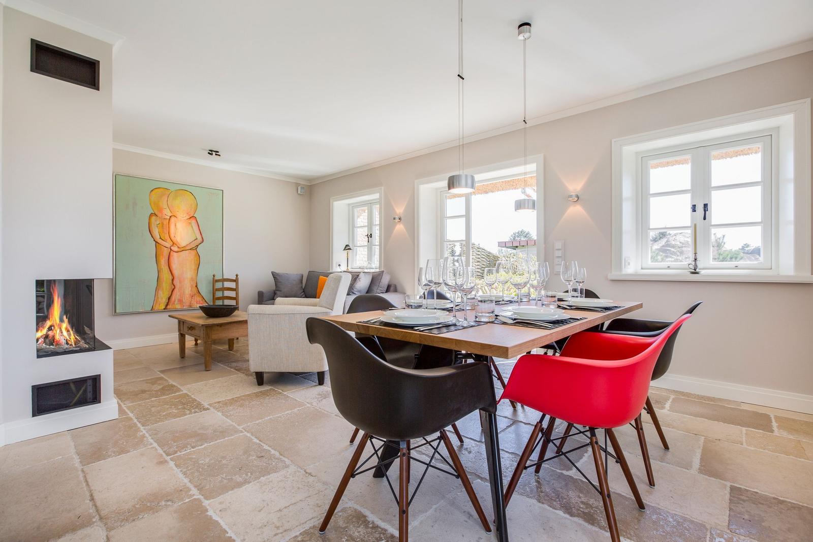 Dining room with table, chairs, and fireplace. Living area with sofa and wall art.