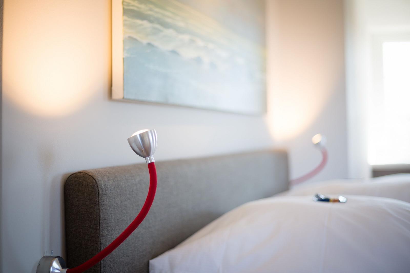 Bed head with red lamps and wall art