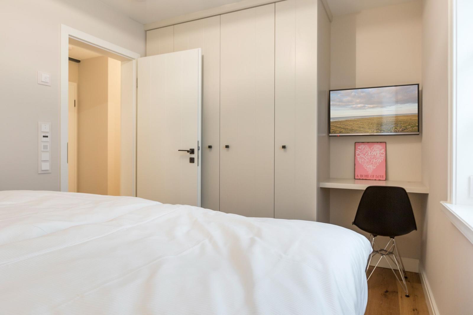 Bedroom with bed, wardrobe, and desk with TV