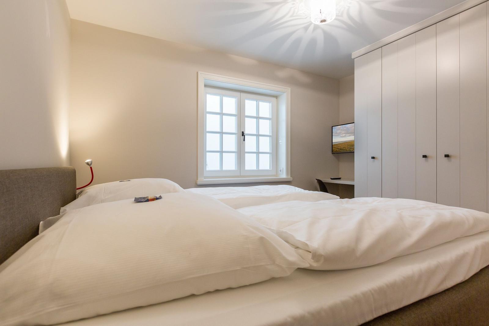 Bedroom with double bed, window, and wardrobe.