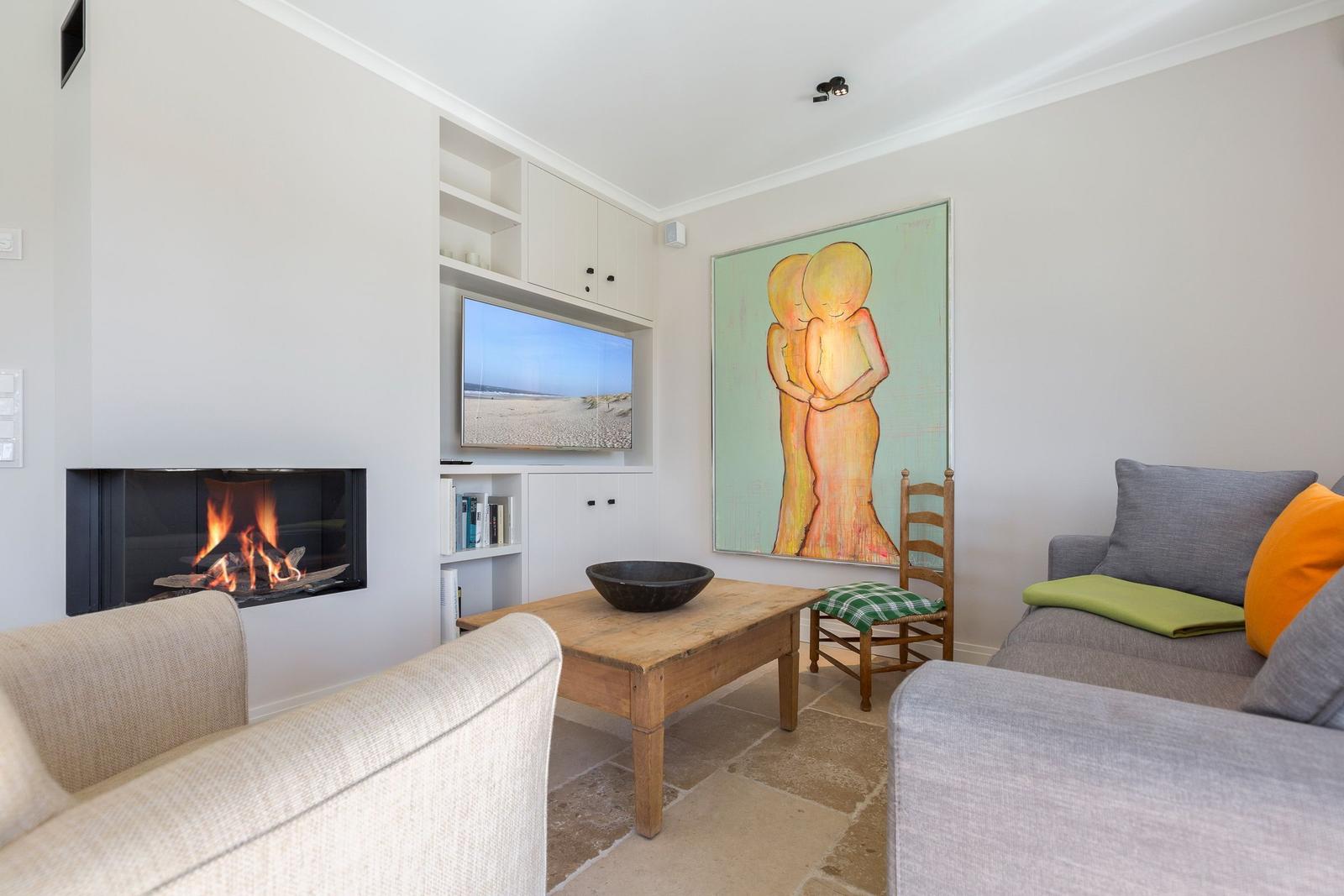 Living room with fireplace, TV, and large wall art.