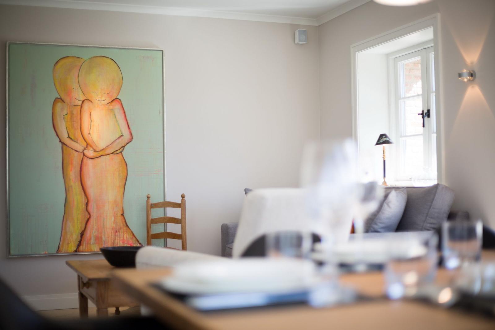 Dining room with table, chairs, and wall art. Window with lamp.