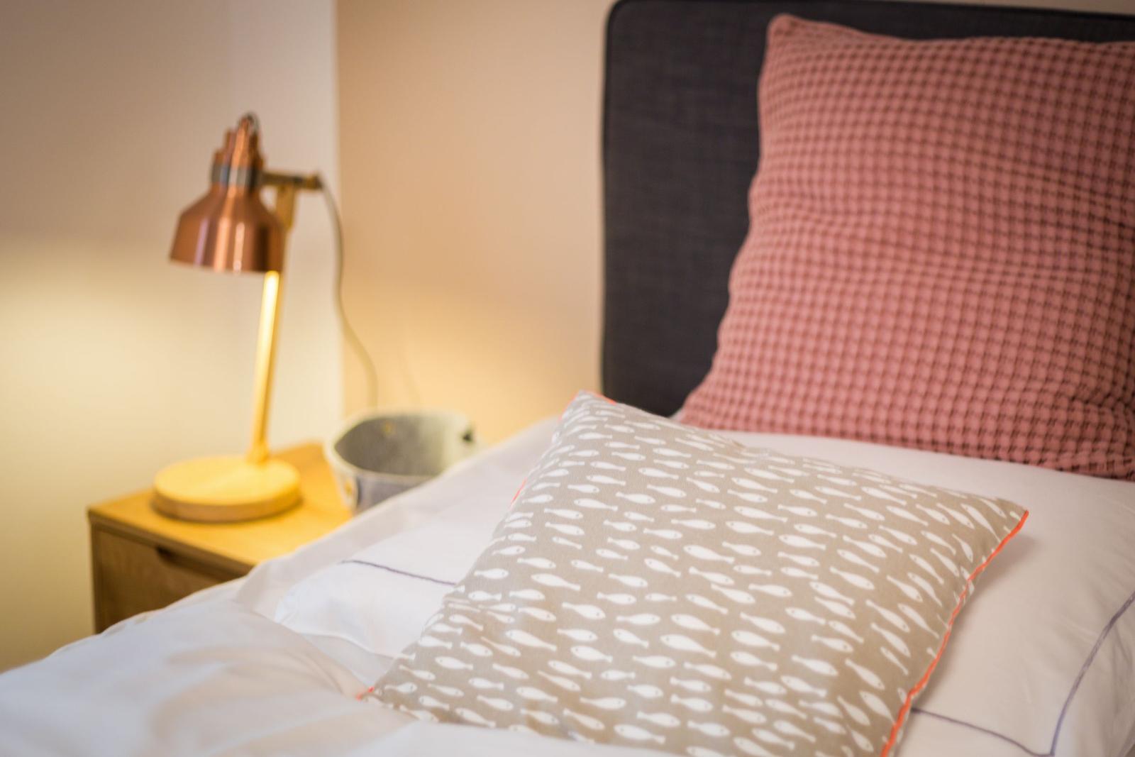 Bettkopf mit Kissen, Nachttisch mit Lampe und Schale