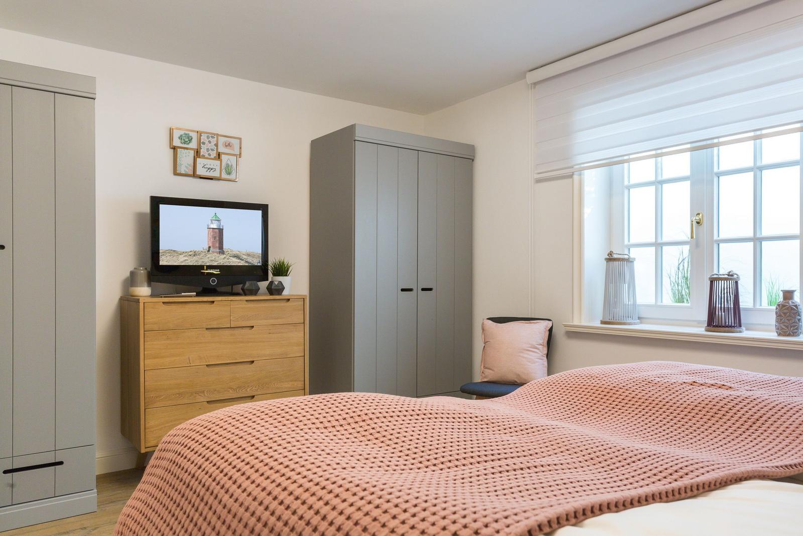 Schlafzimmer mit Bett, Kleiderschrank und Fernseher.