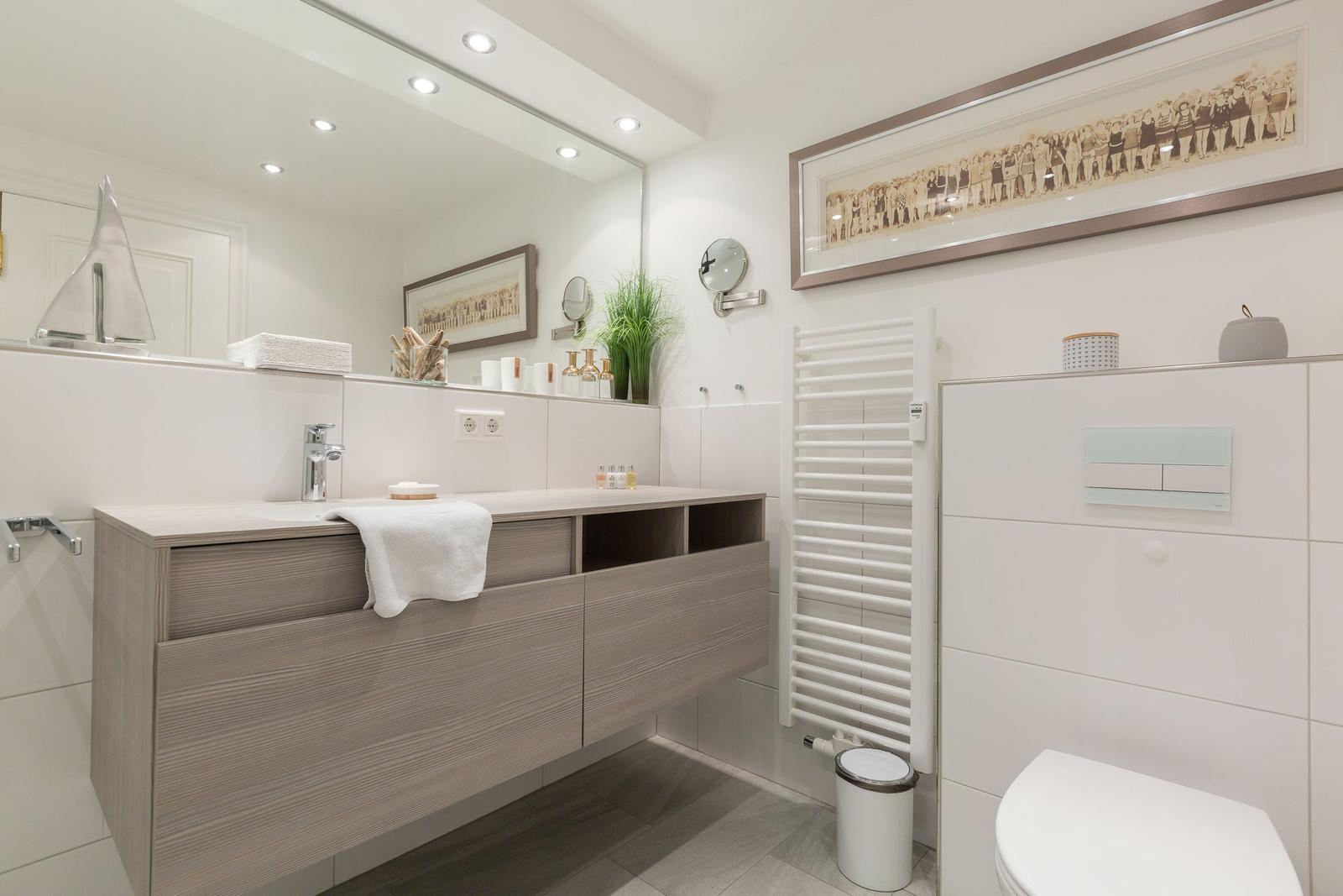 Moderne Badezimmer mit Waschtisch, Spiegel und Toilette.