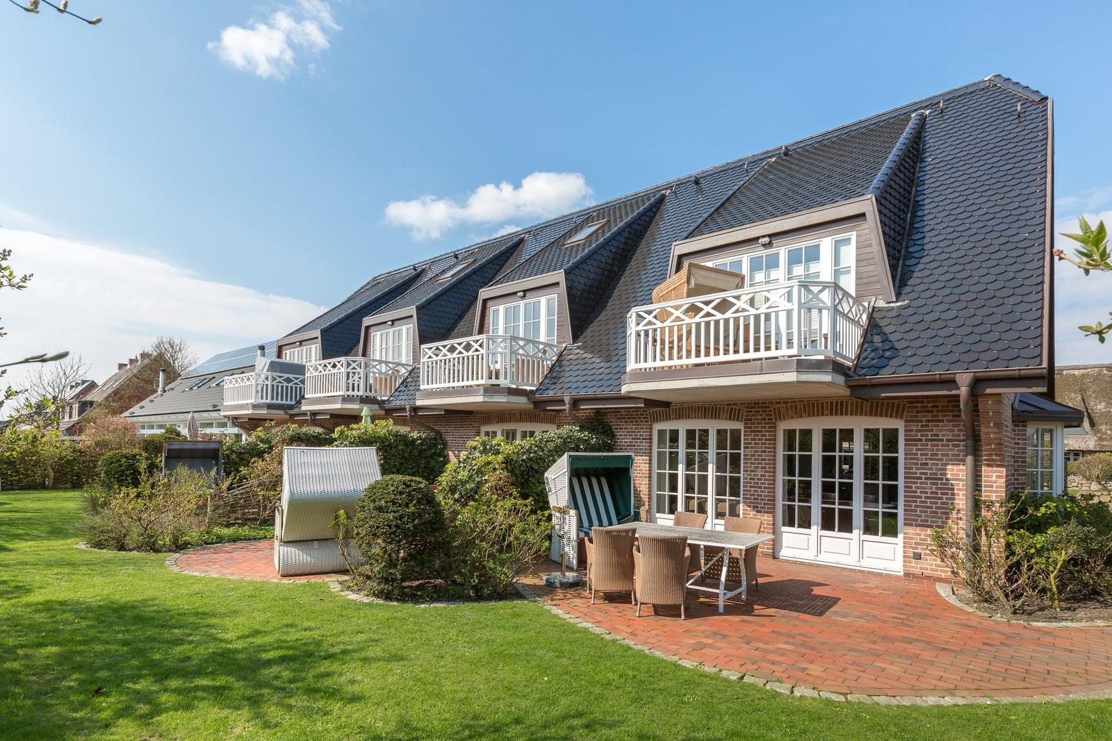 Ferienhaus mit Balkonen, Garten und Terrasse mit Gartenmöbeln.