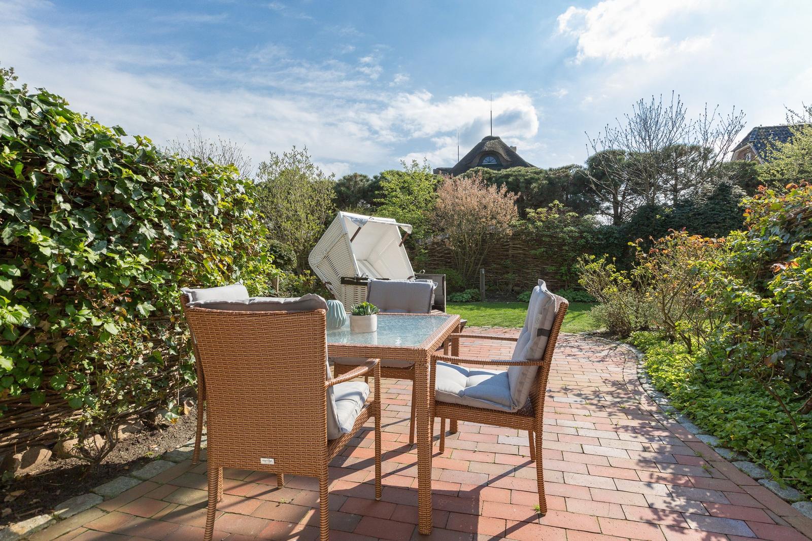 Terrasse mit Sitzgruppe und Blick auf Garten und Haus.