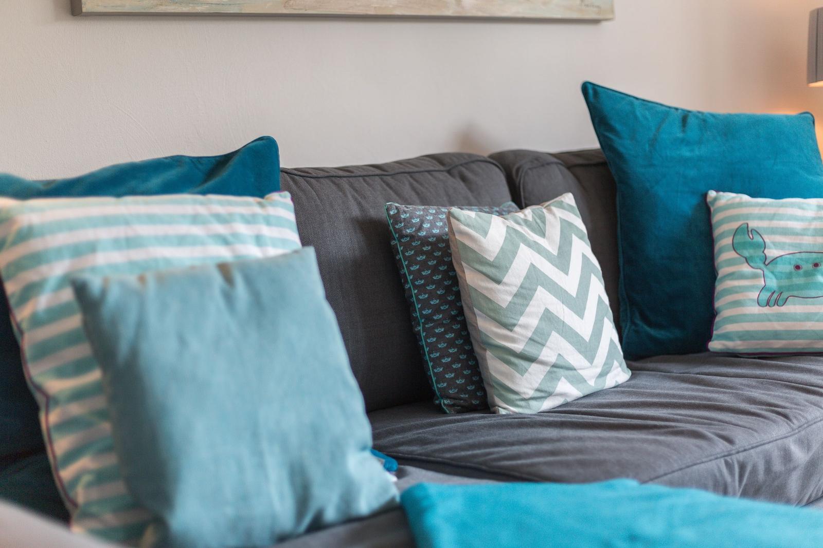 Ein grauer Sofa mit blauen und gestreiften Kissen.