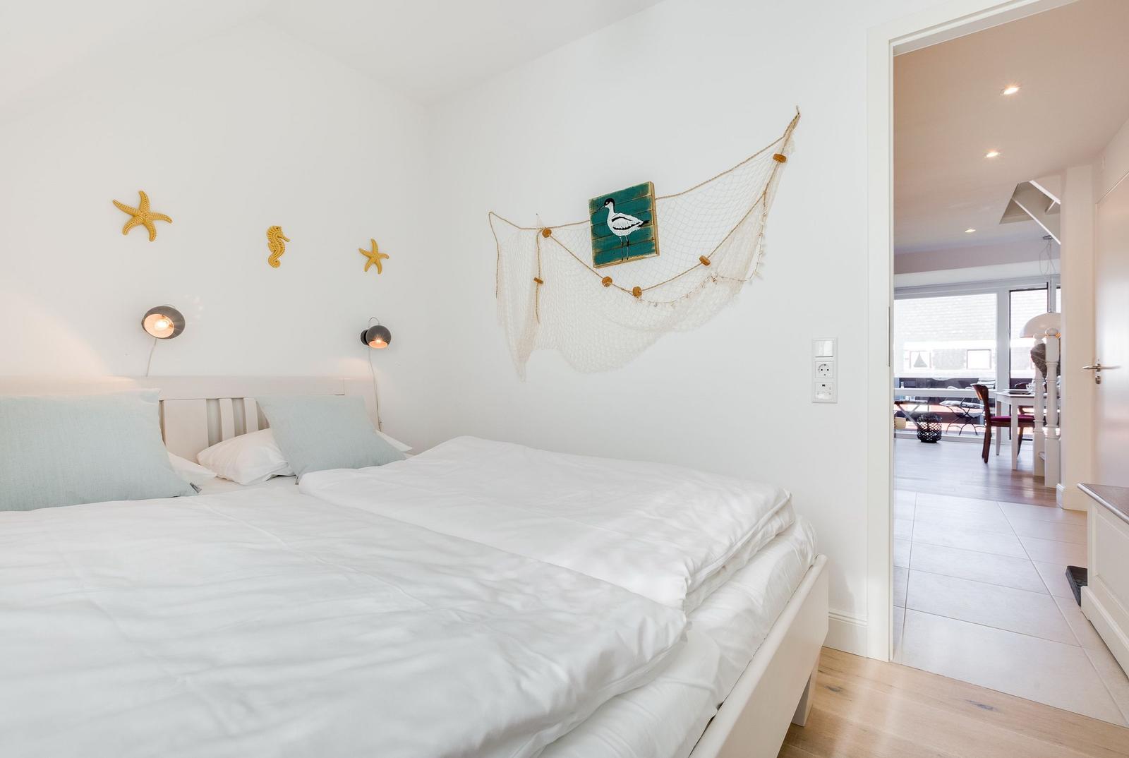 Bedroom with bed, wall decor, and view into the kitchen.