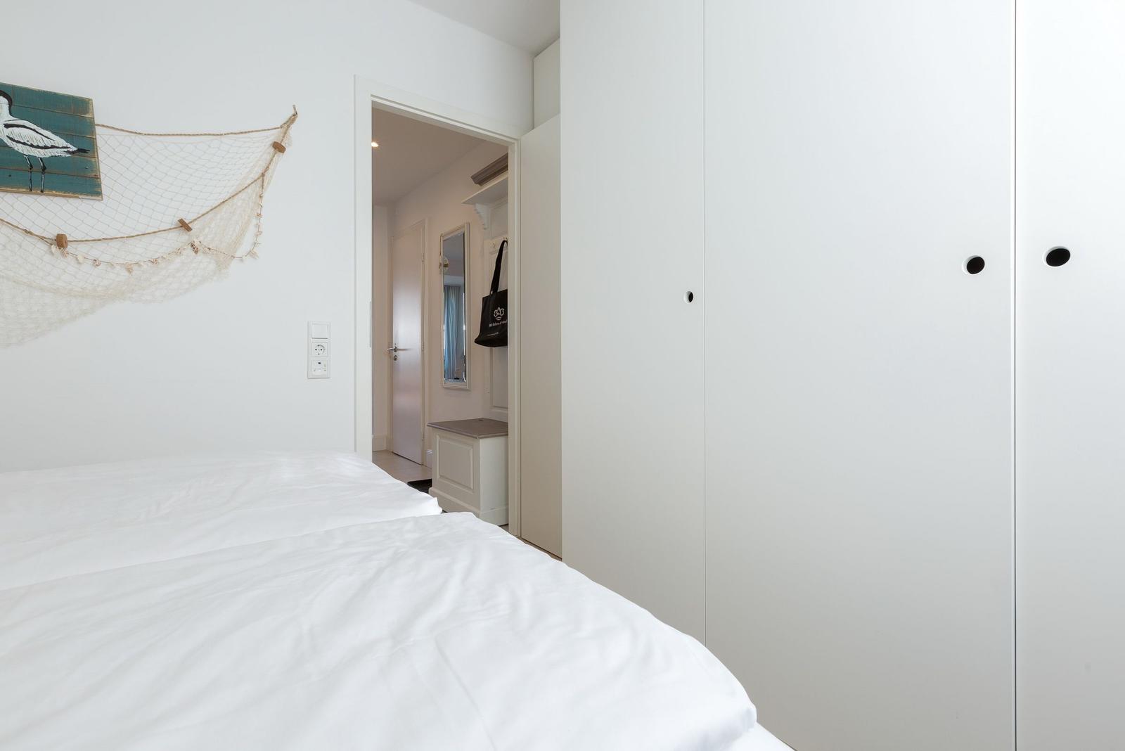 Bedroom with white bed, wardrobe, and wall decoration.