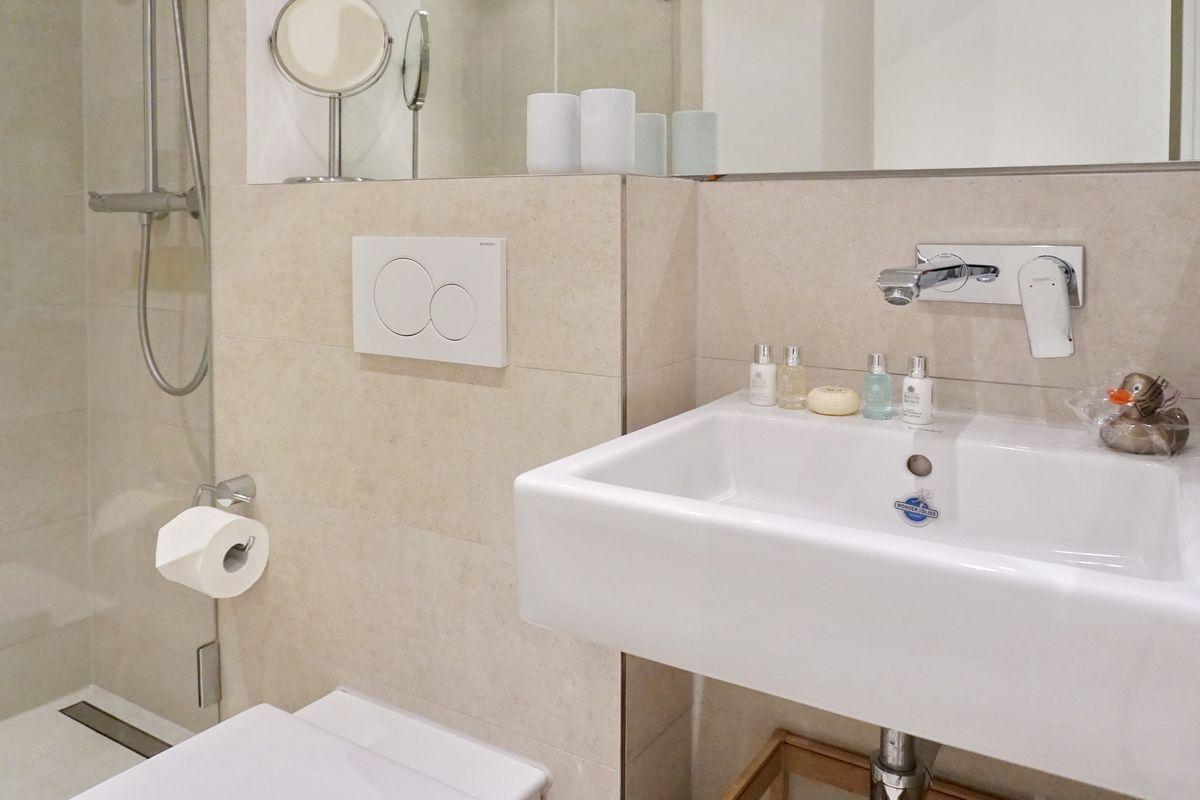 Bathroom with shower, sink, and toilet. Soap and rubber duck on the sink.
