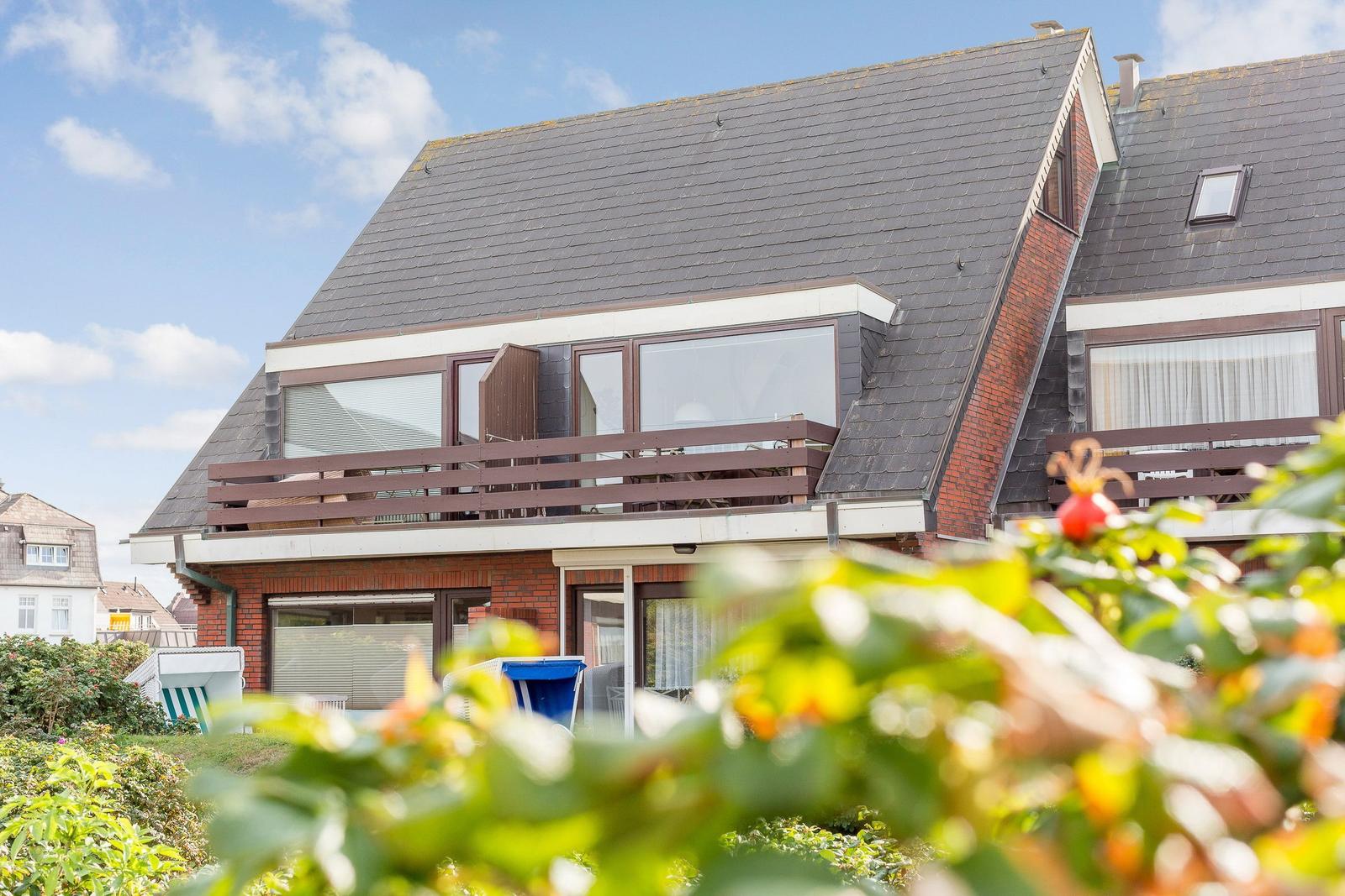House with balcony and skylight, surrounded by greenery.