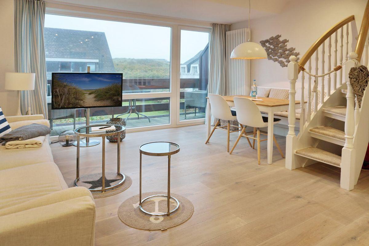 Living and dining area with TV, table, chairs, and staircase.