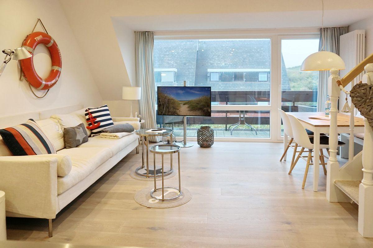 Living room with sofa, TV, and dining area. View of terrace and roof.