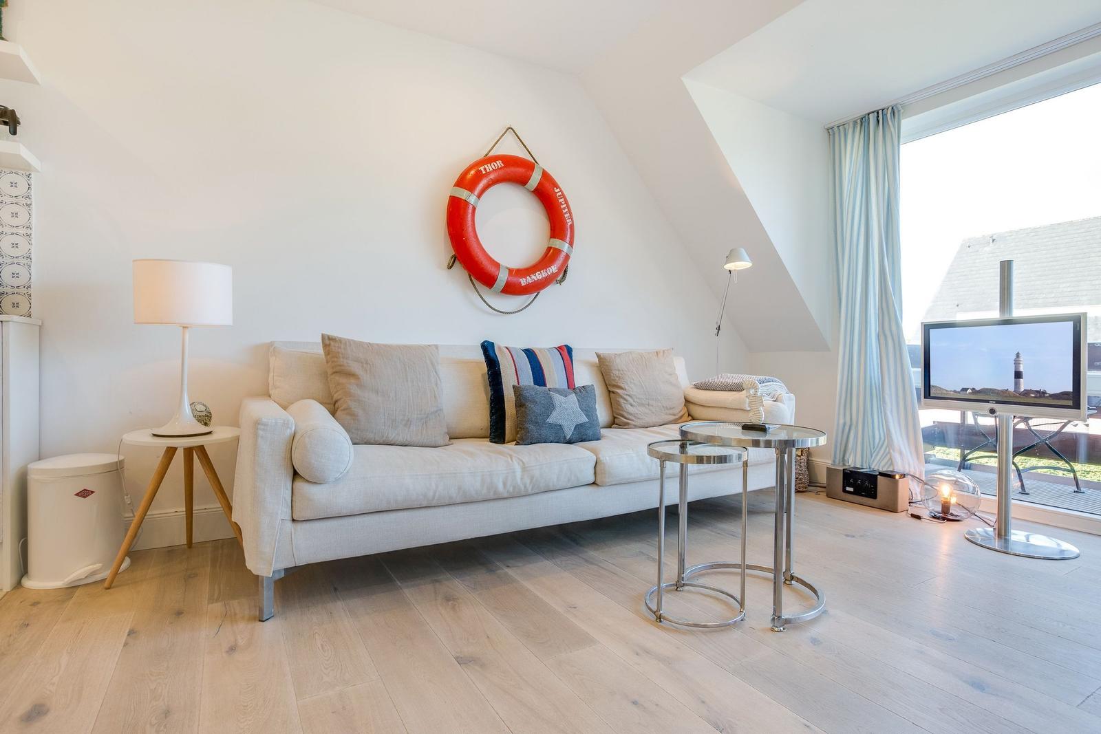 Living room with sofa, lifebuoy on wall, and TV.