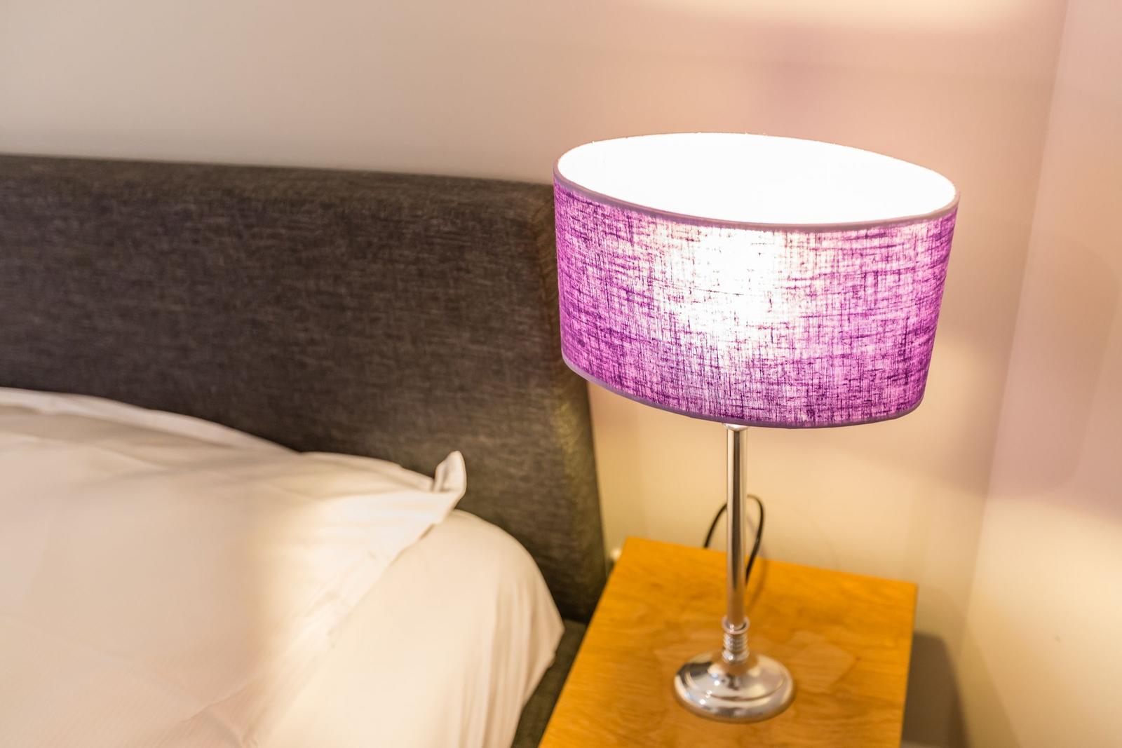 Bettkopfteil mit Nachttisch und Lampe mit lila Schirm